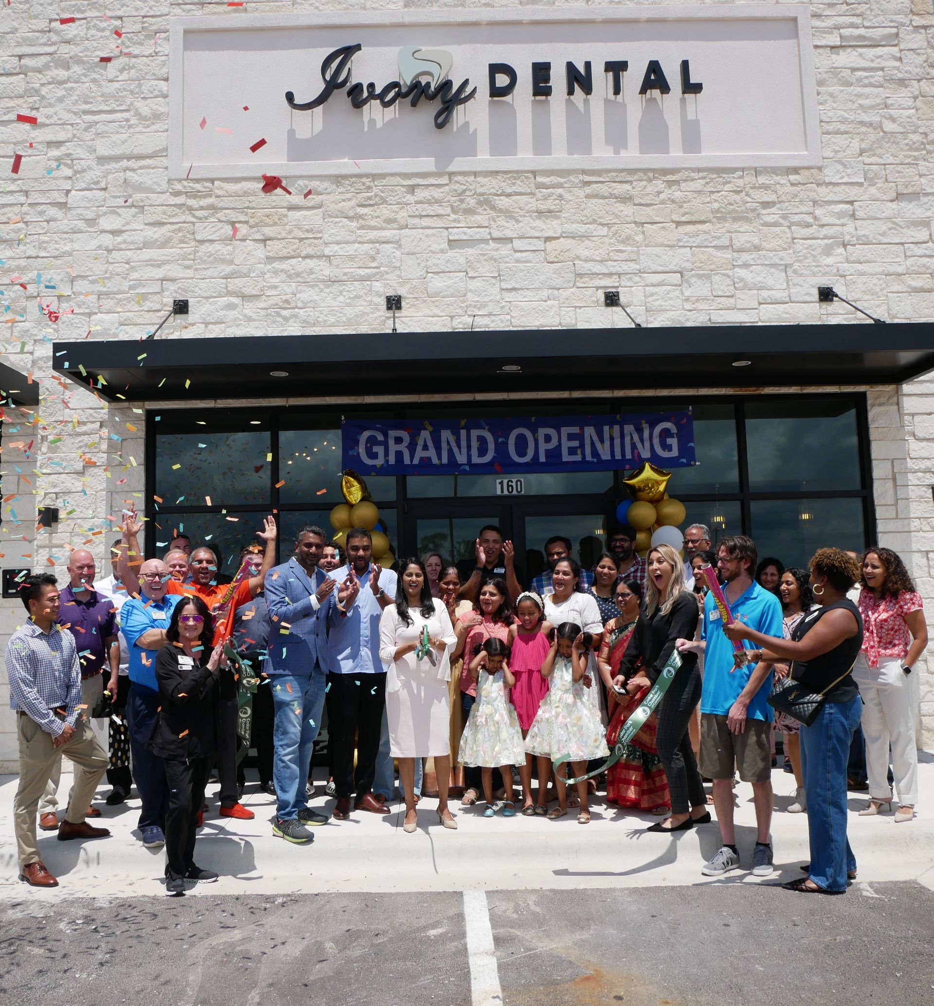 A group of people standing in front of a building that says grand opening