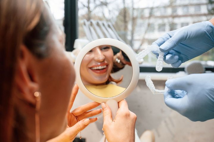 A woman is looking at her smile in a mirror.
