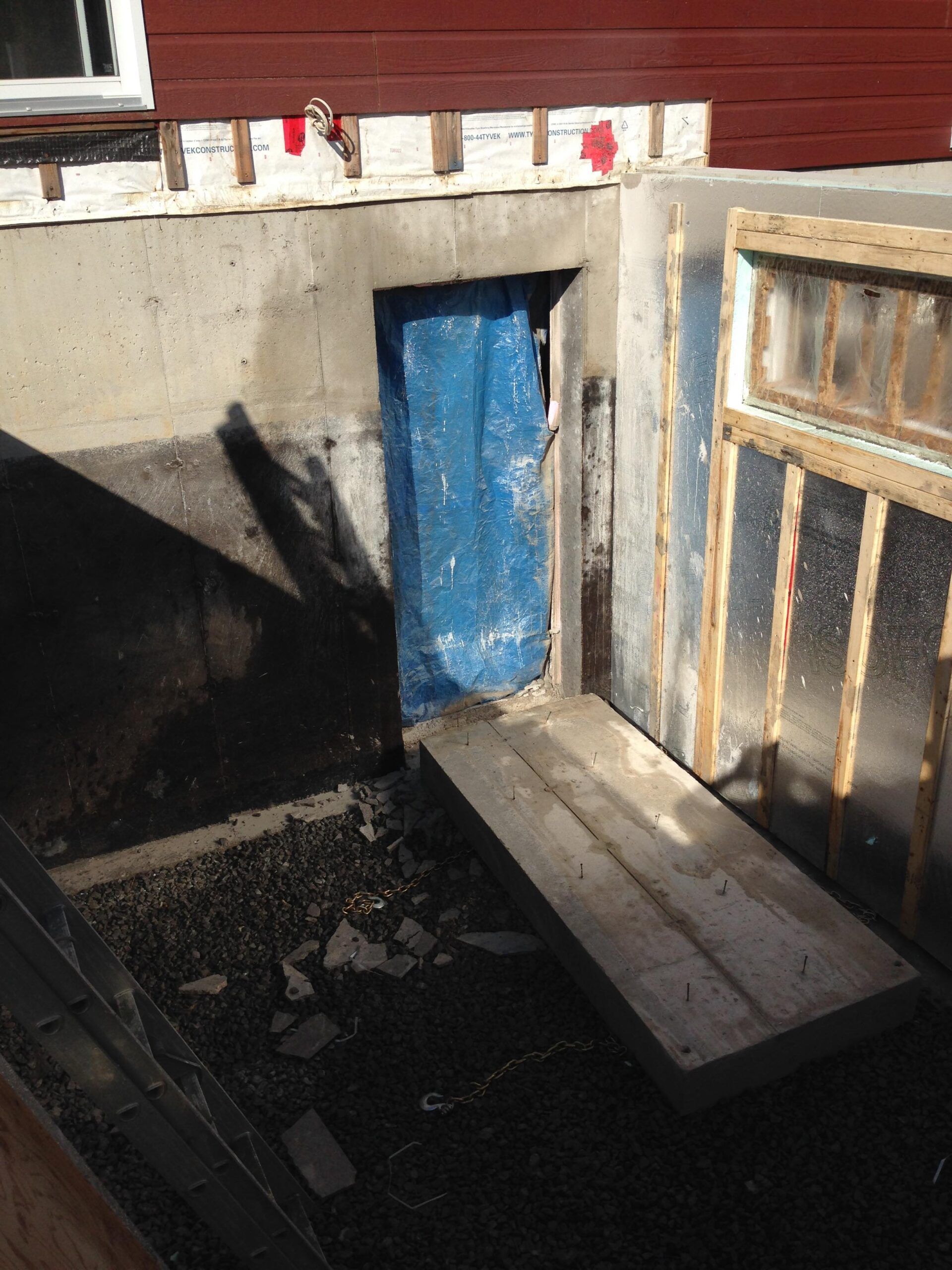 Un sous-sol en construction avec une bâche bleue recouvrant la porte