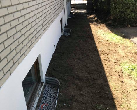 Un bâtiment en briques blanches avec un chemin de terre qui y mène