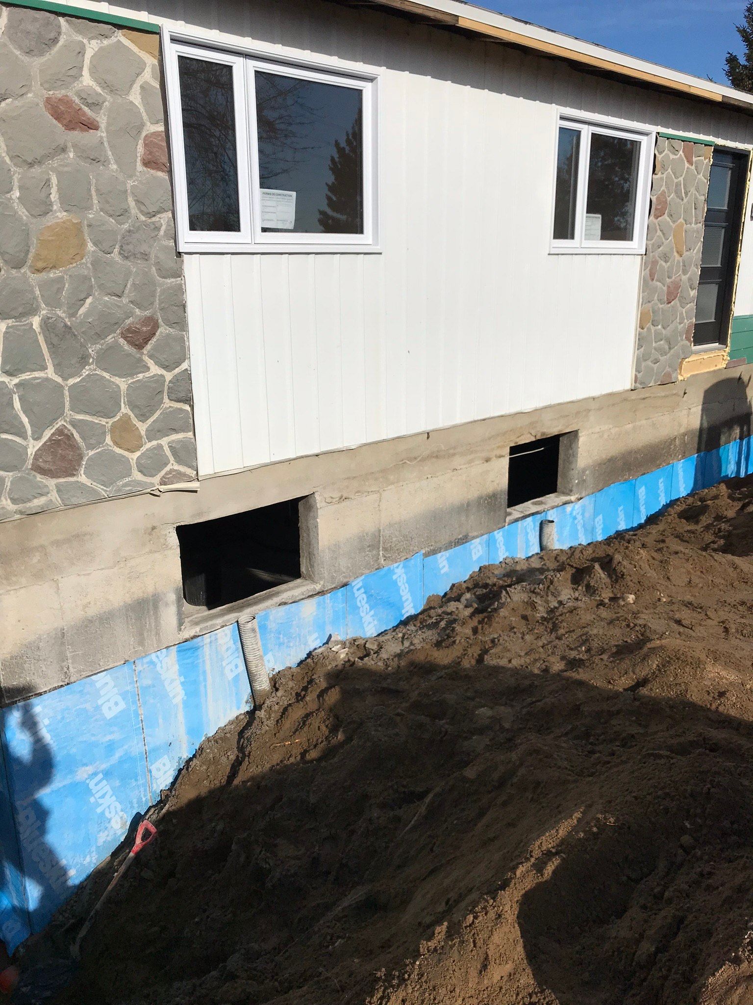 Une maison blanche avec un mur de pierre est en construction.