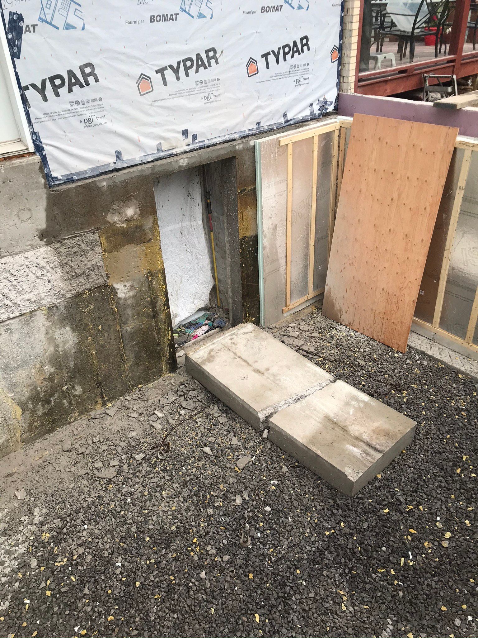 Une dalle de béton repose sur un tas de gravier à côté d'un mur.