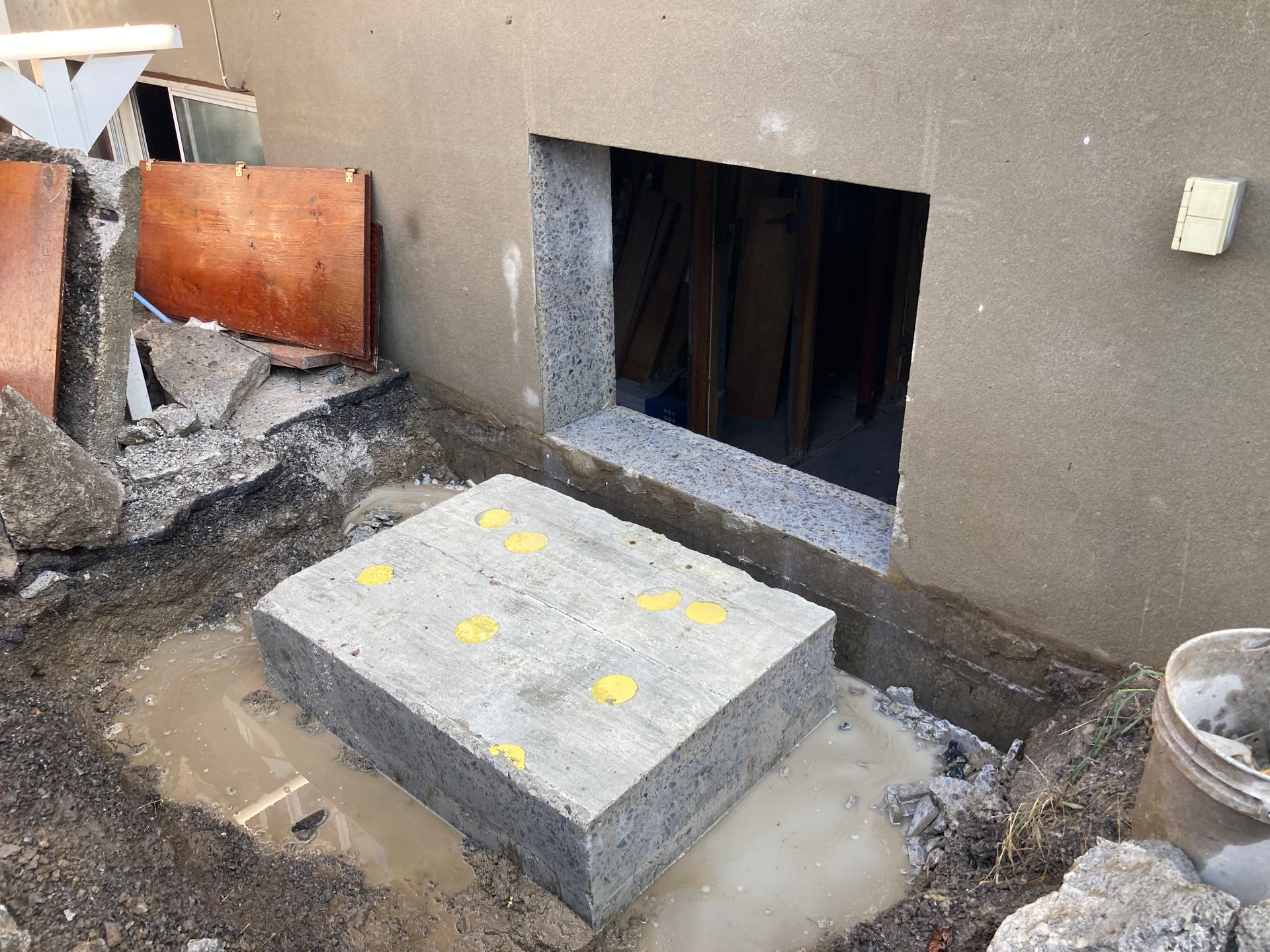 Un bloc de béton repose dans la terre à côté d'une fenêtre.