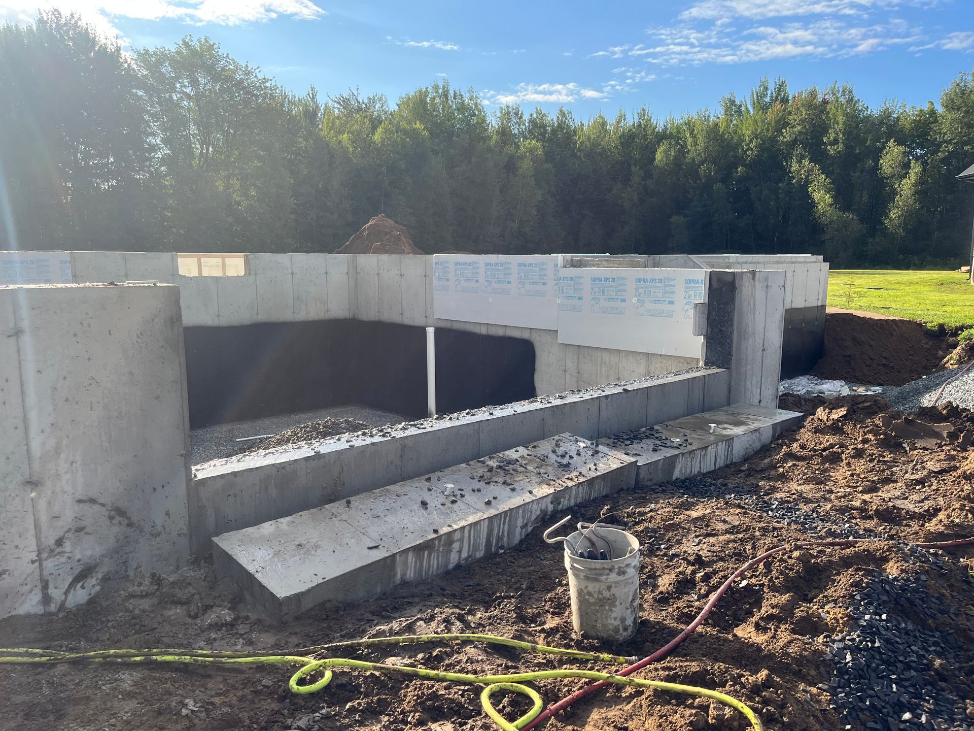 Un mur de béton est en cours de construction dans un champ avec des arbres en arrière-plan.