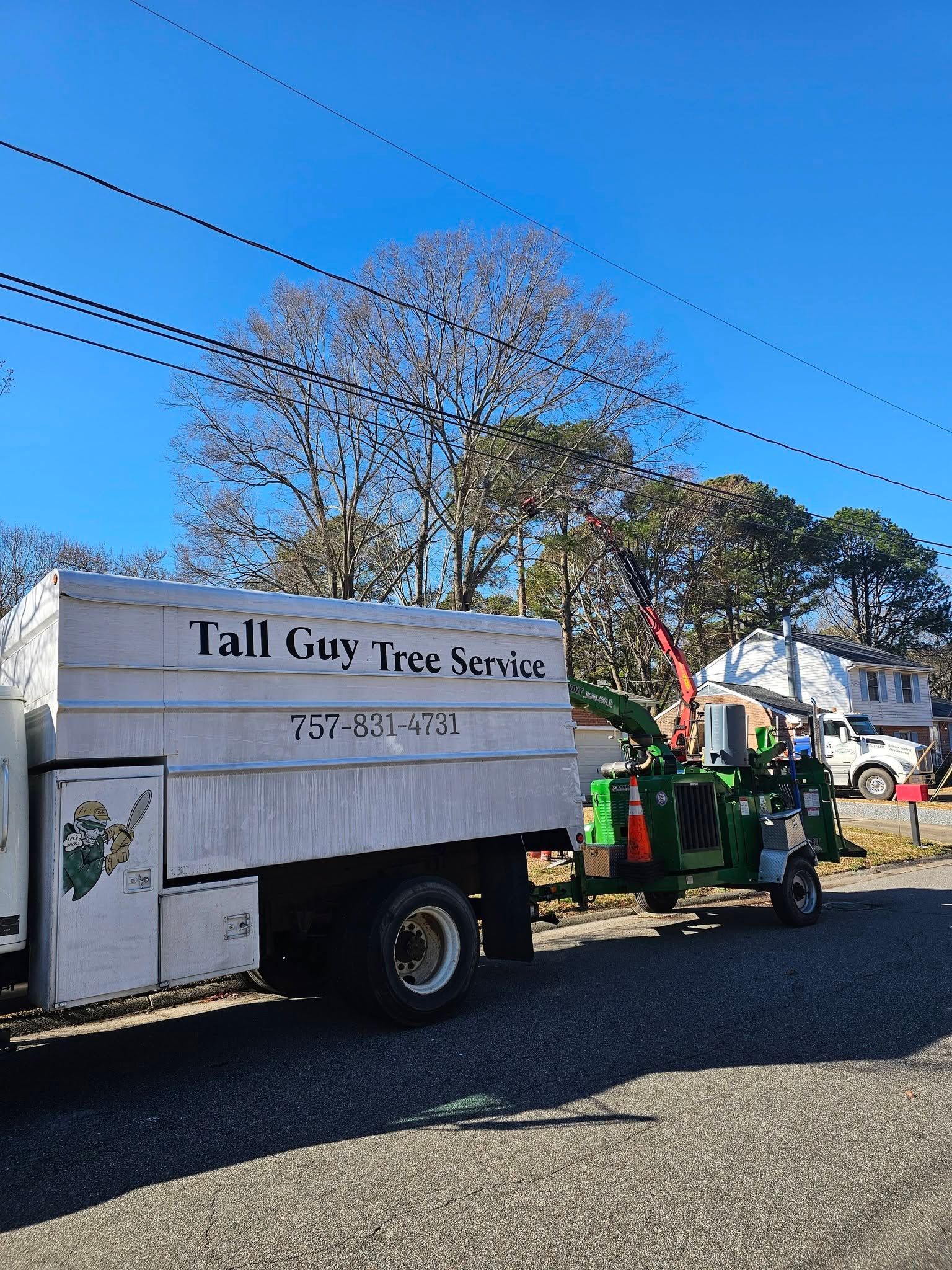 Tree service truck and equipment on a gravel road under a blue sky