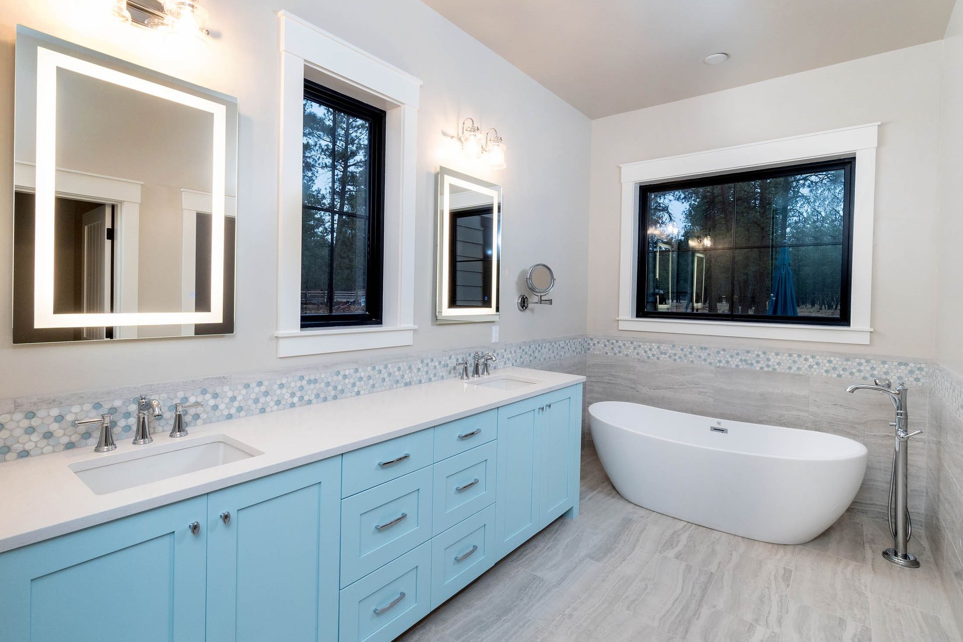 A bathroom with two sinks , two mirrors and a bathtub.