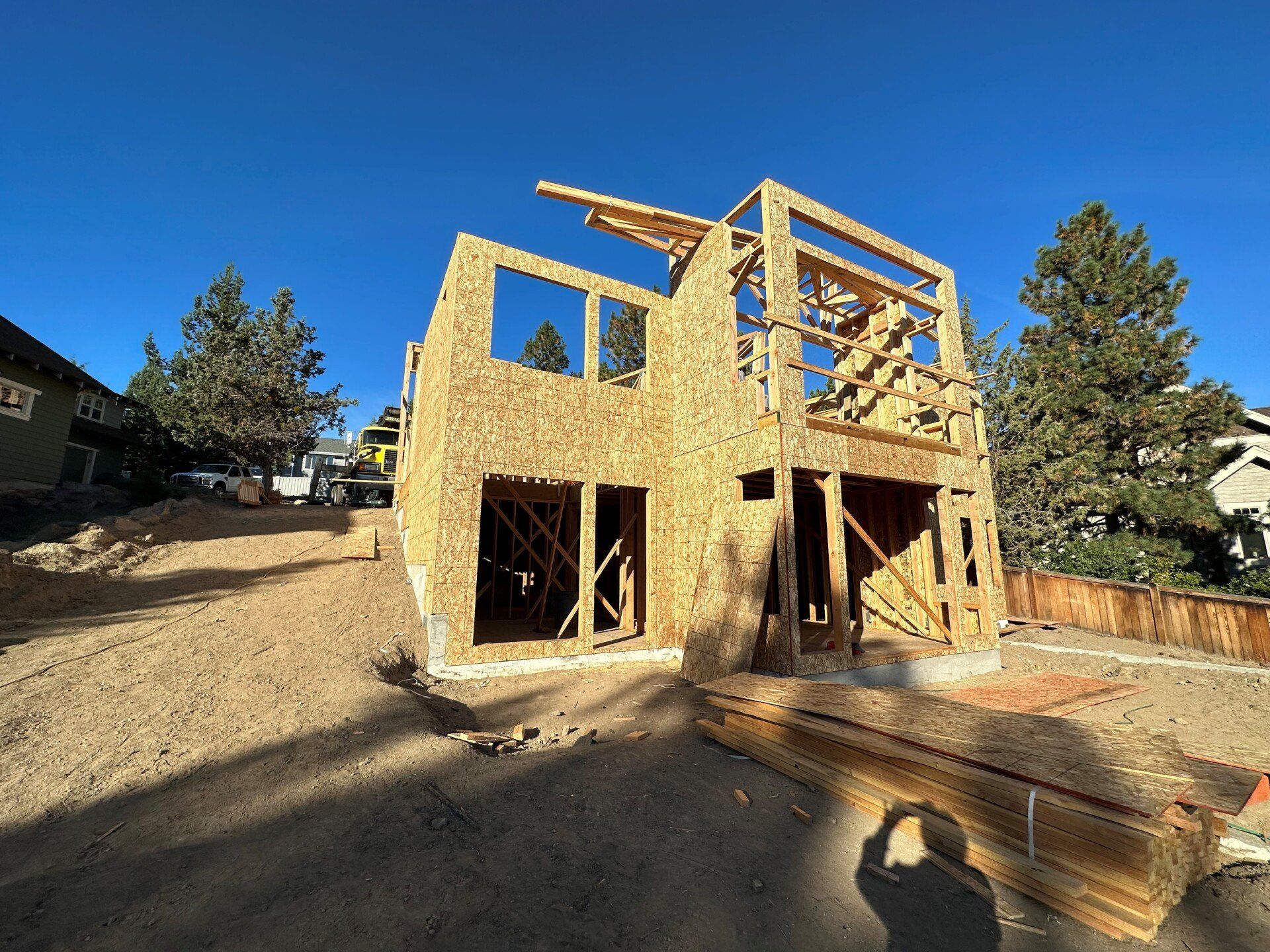 A house is being built on a dirt hill with a blue sky in the background.