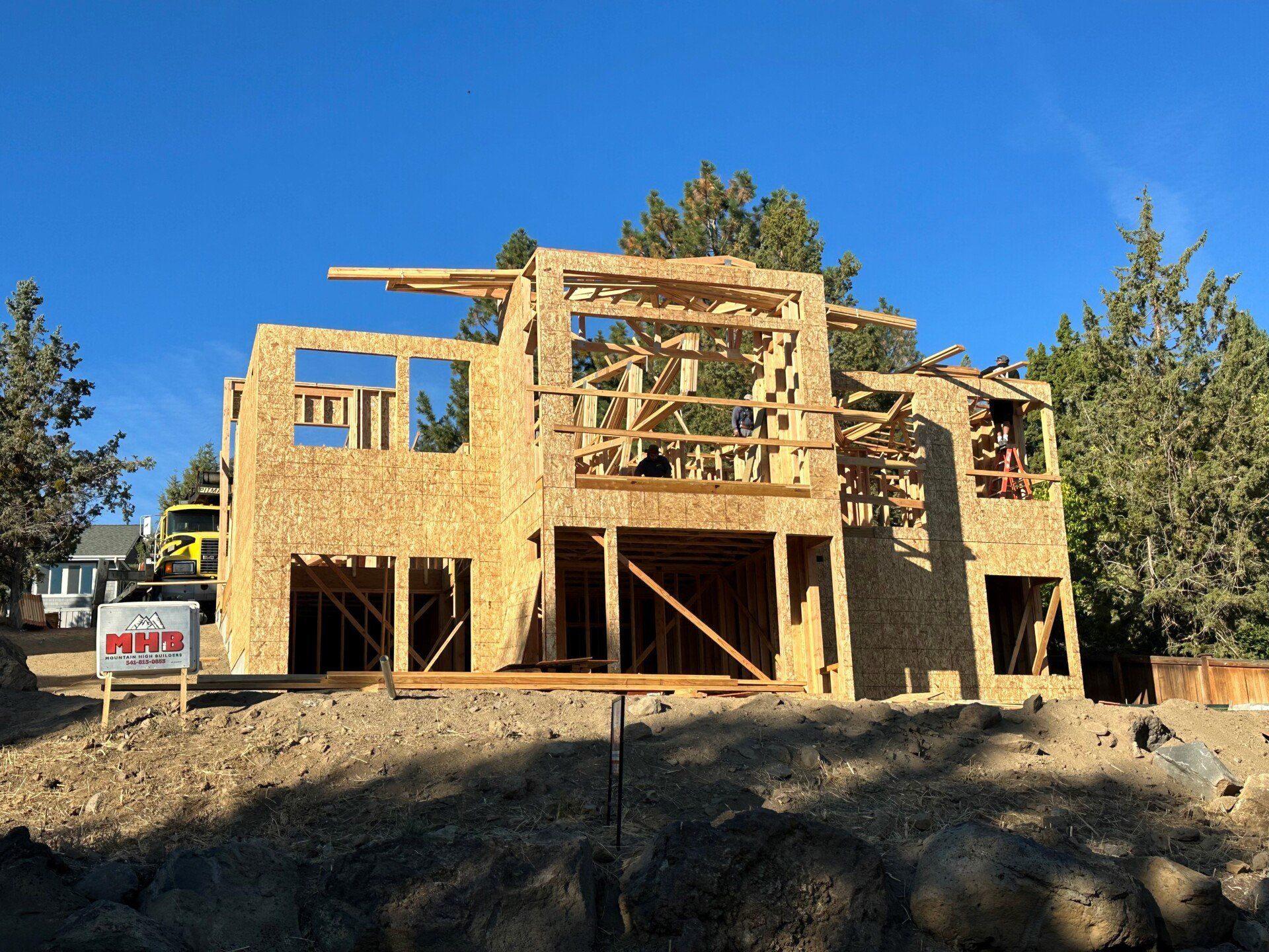 A large wooden house is being built on top of a dirt hill.