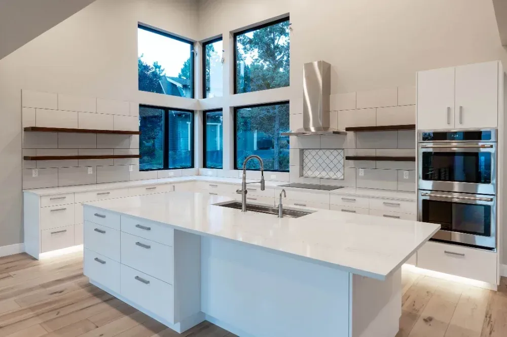 A kitchen with white cabinets , stainless steel appliances , and a large island.