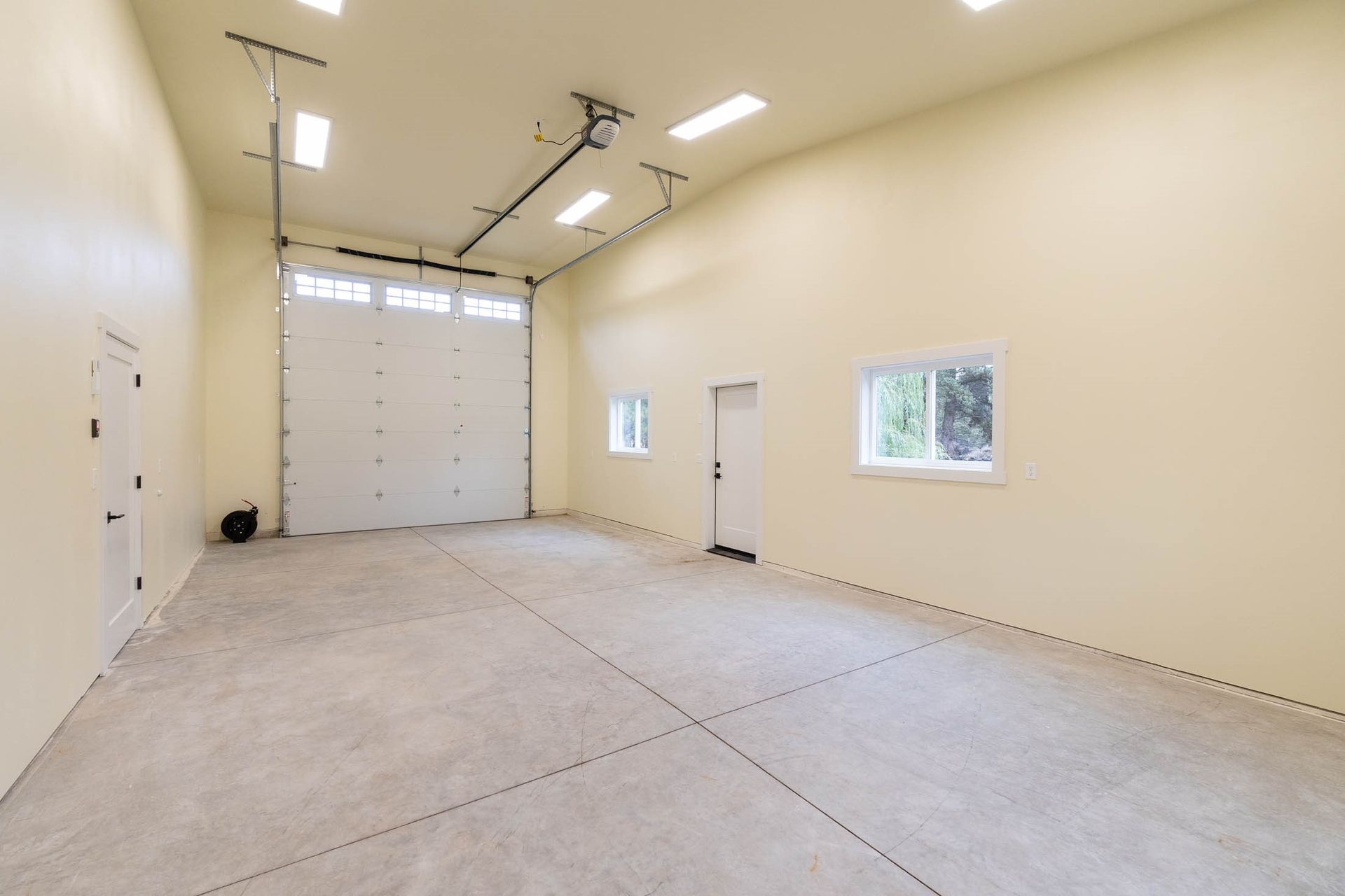 A large empty garage with a garage door open and a ceiling fan.