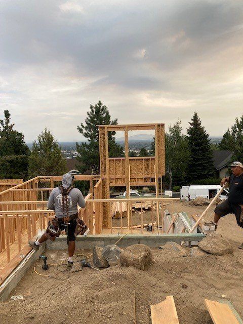 A group of construction workers are working on a house under construction.