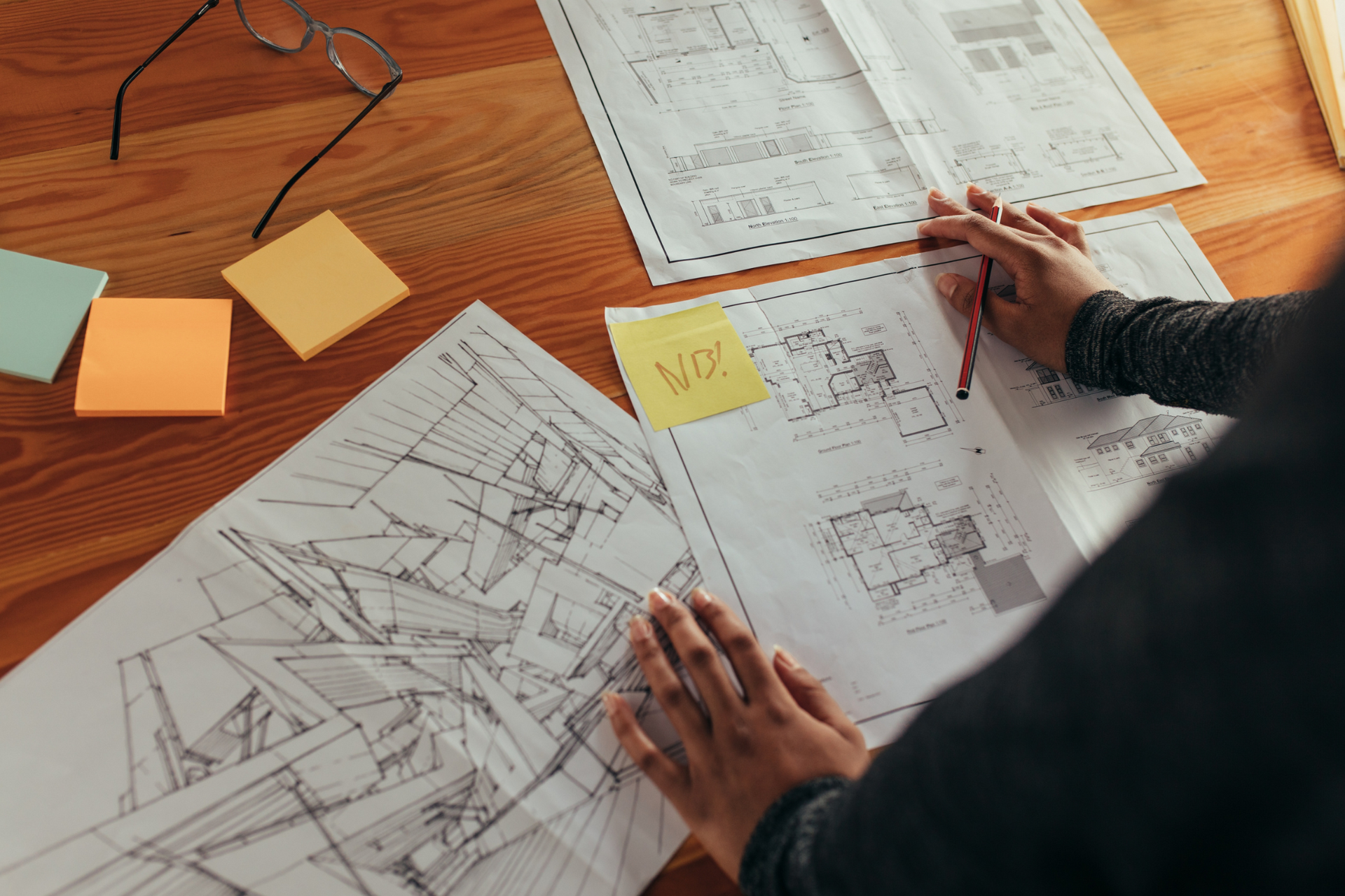 A person is sitting at a table looking at architectural drawings.