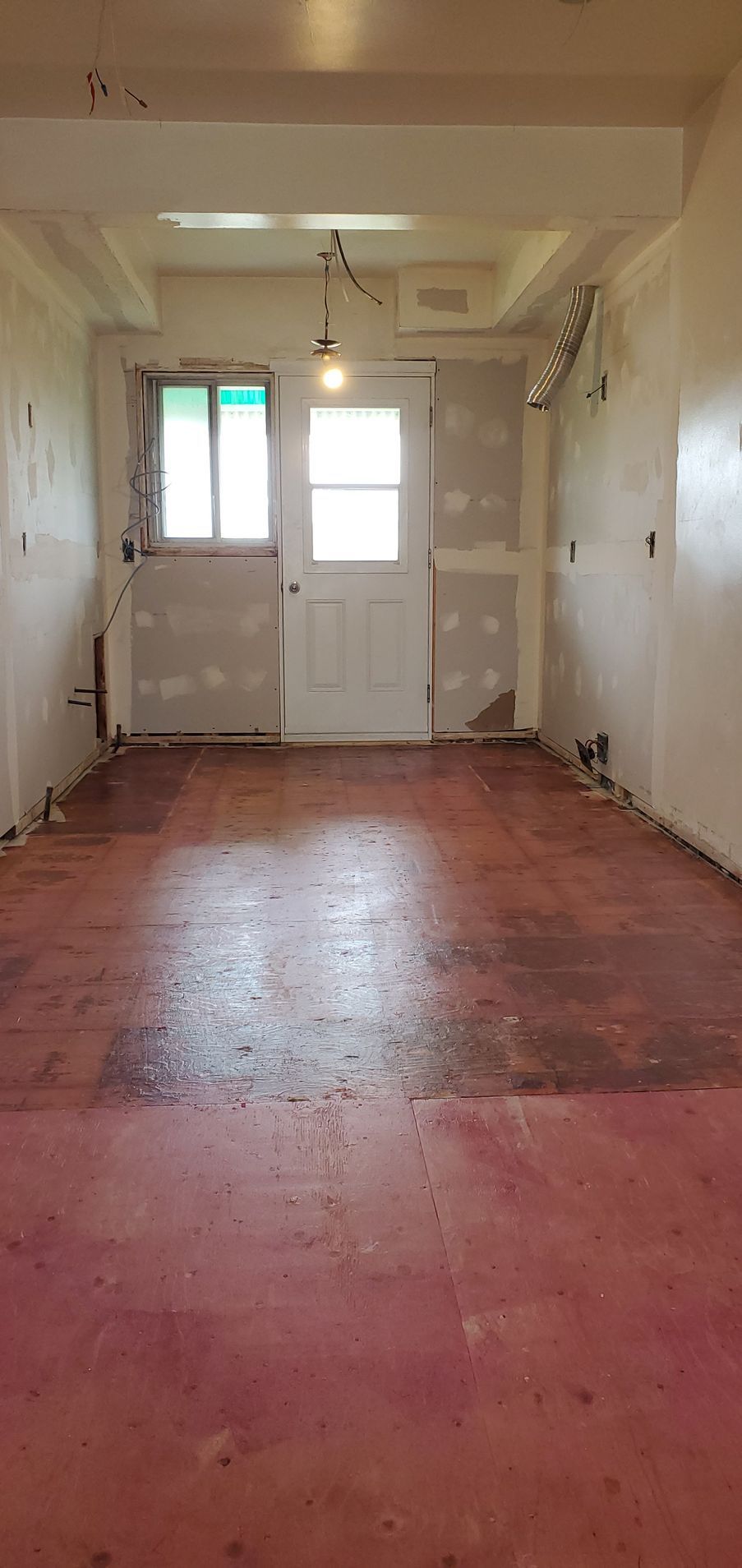 An empty room with a red floor and a white door.