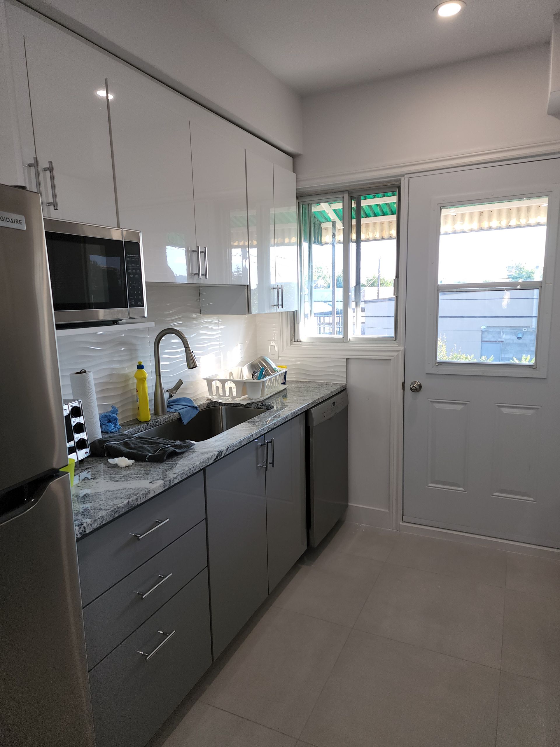 A kitchen with a sink , refrigerator , microwave , and dishwasher.