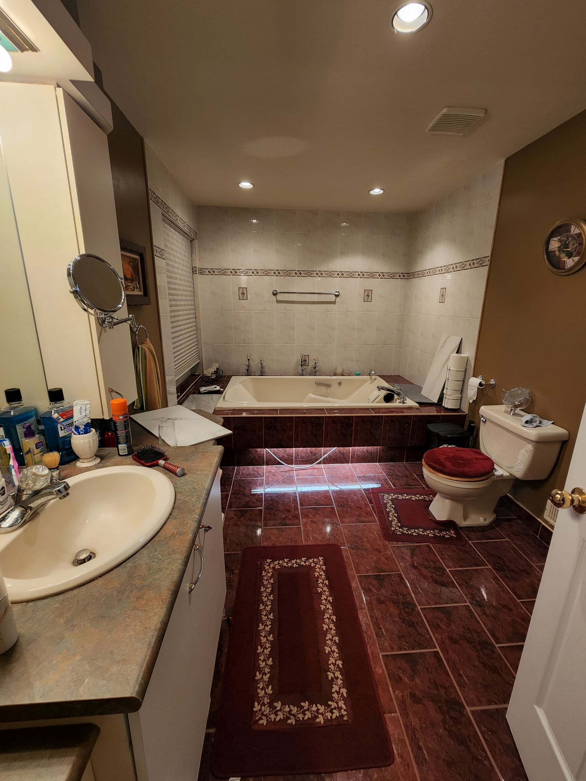 A bathroom with a tub , sink , toilet and mirror