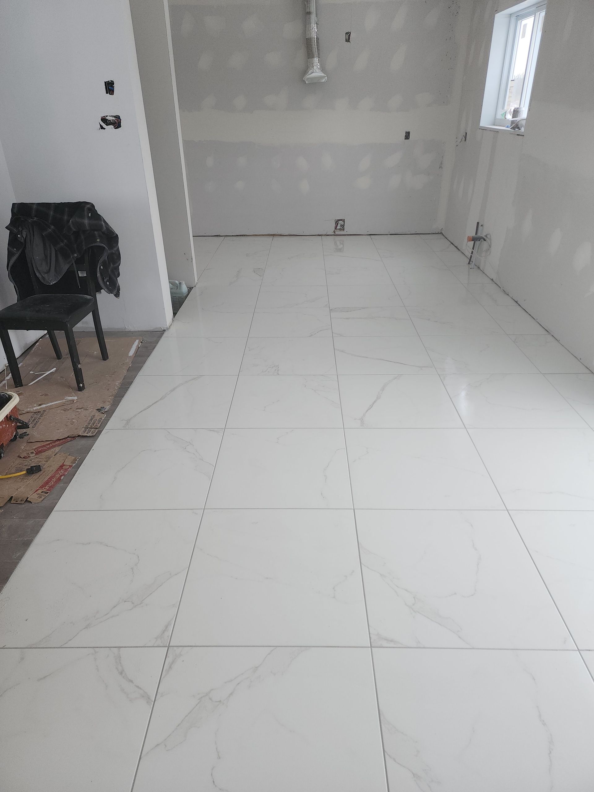 A room with white tiles on the floor and a chair in the corner.