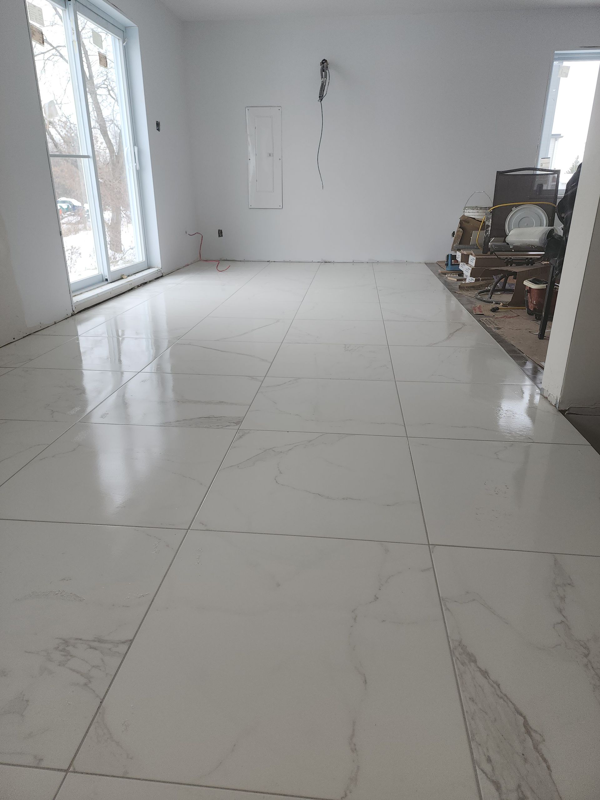A large white tiled floor in a room with a fireplace.