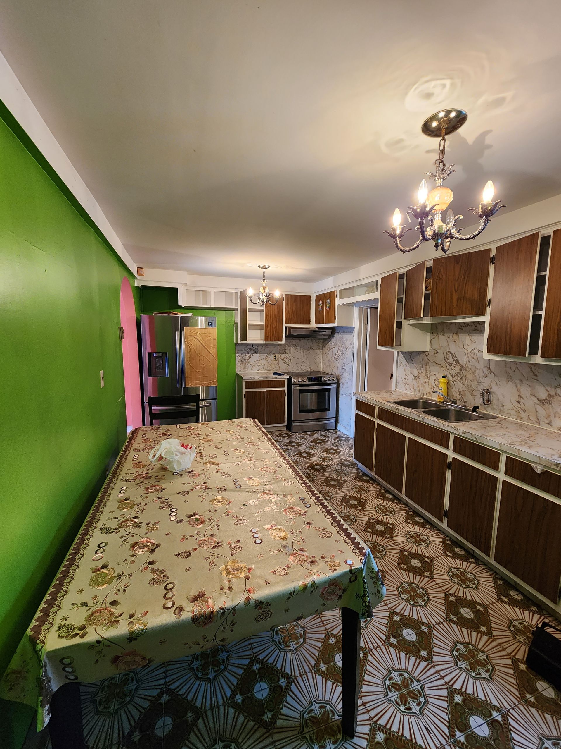 A kitchen with a long table and a chandelier hanging from the ceiling