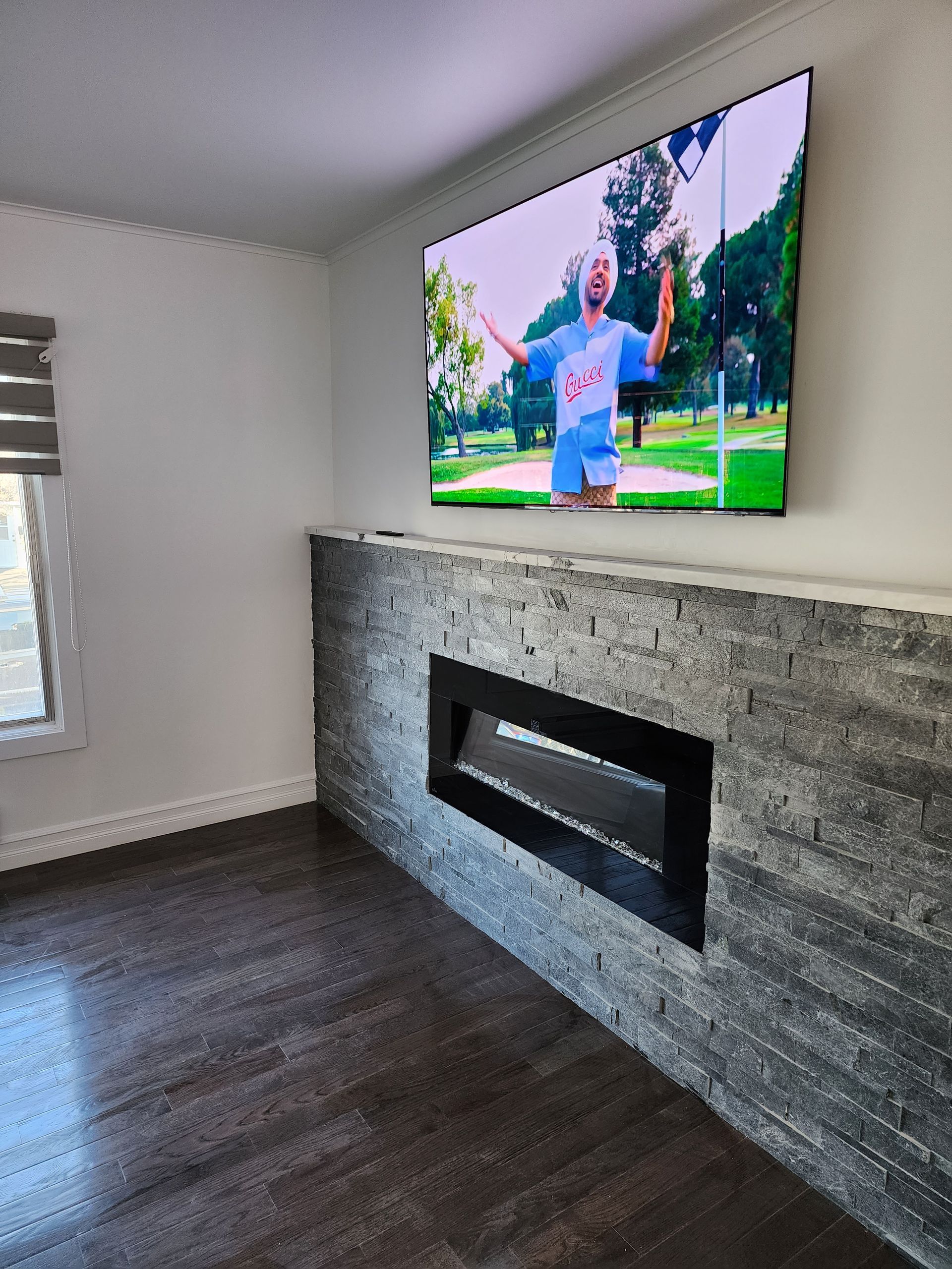 A living room with a fireplace and a flat screen tv on the wall.