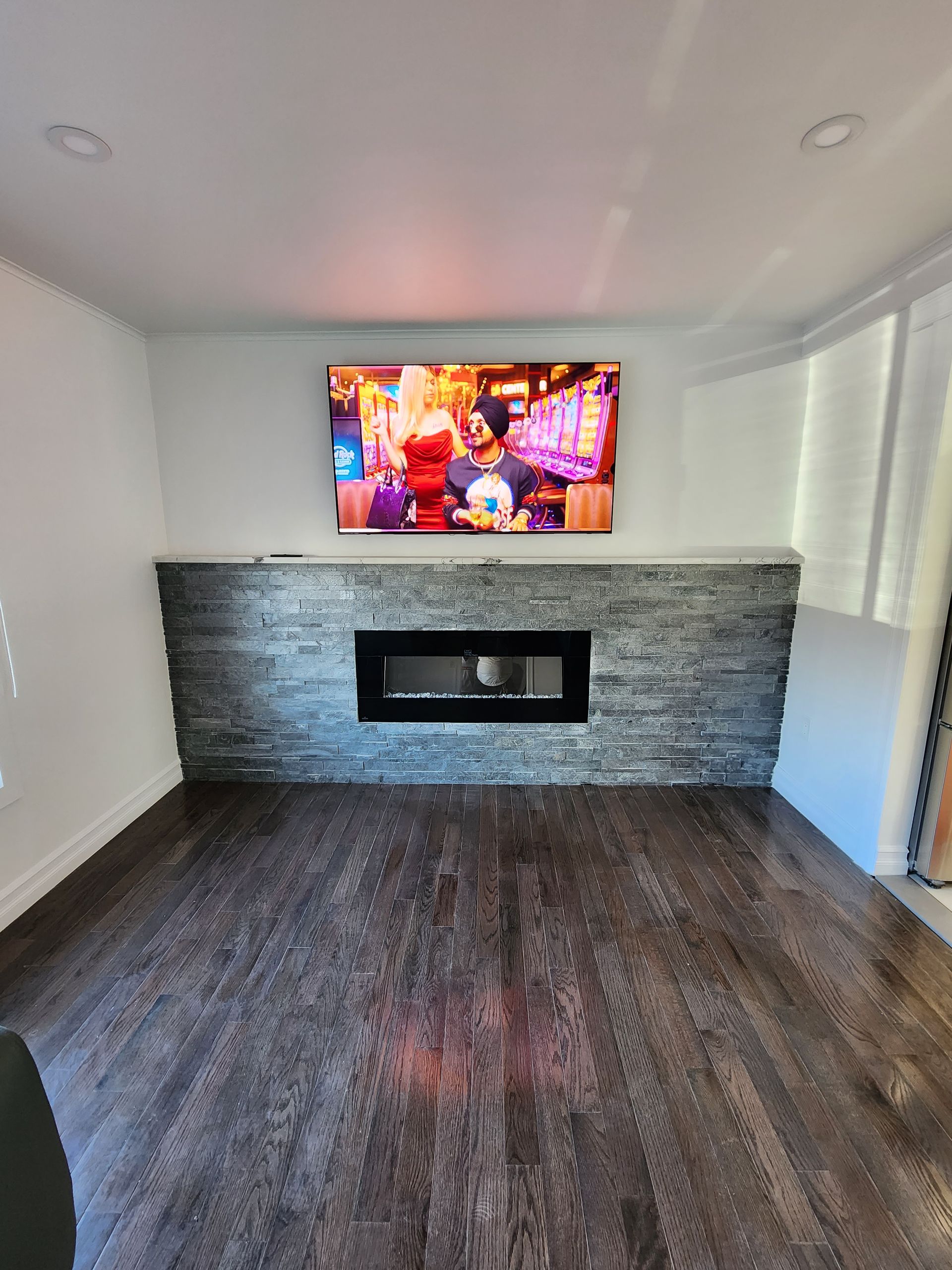 A living room with a fireplace and a flat screen tv on the wall.