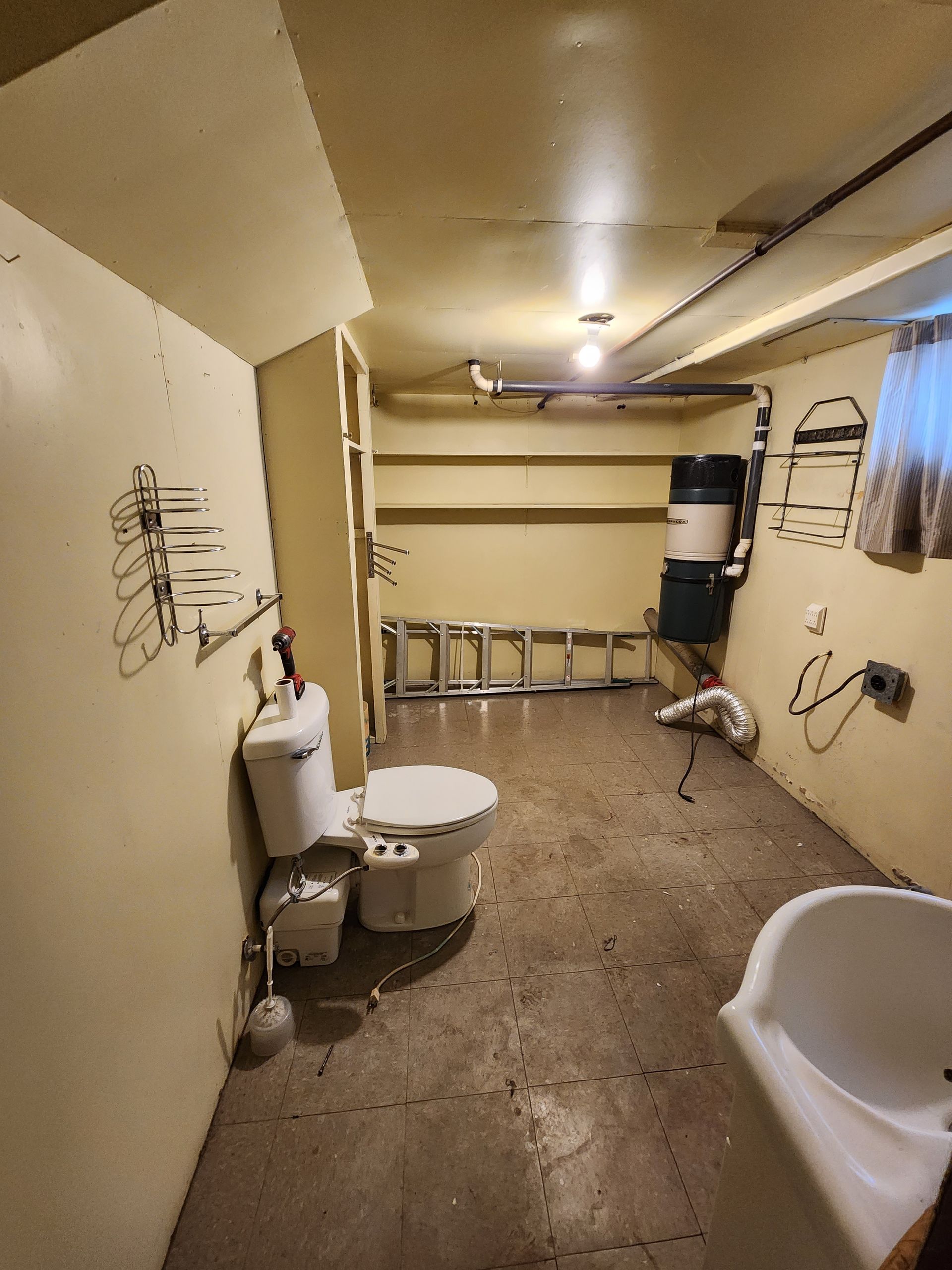 A bathroom with a toilet , sink and ladder.