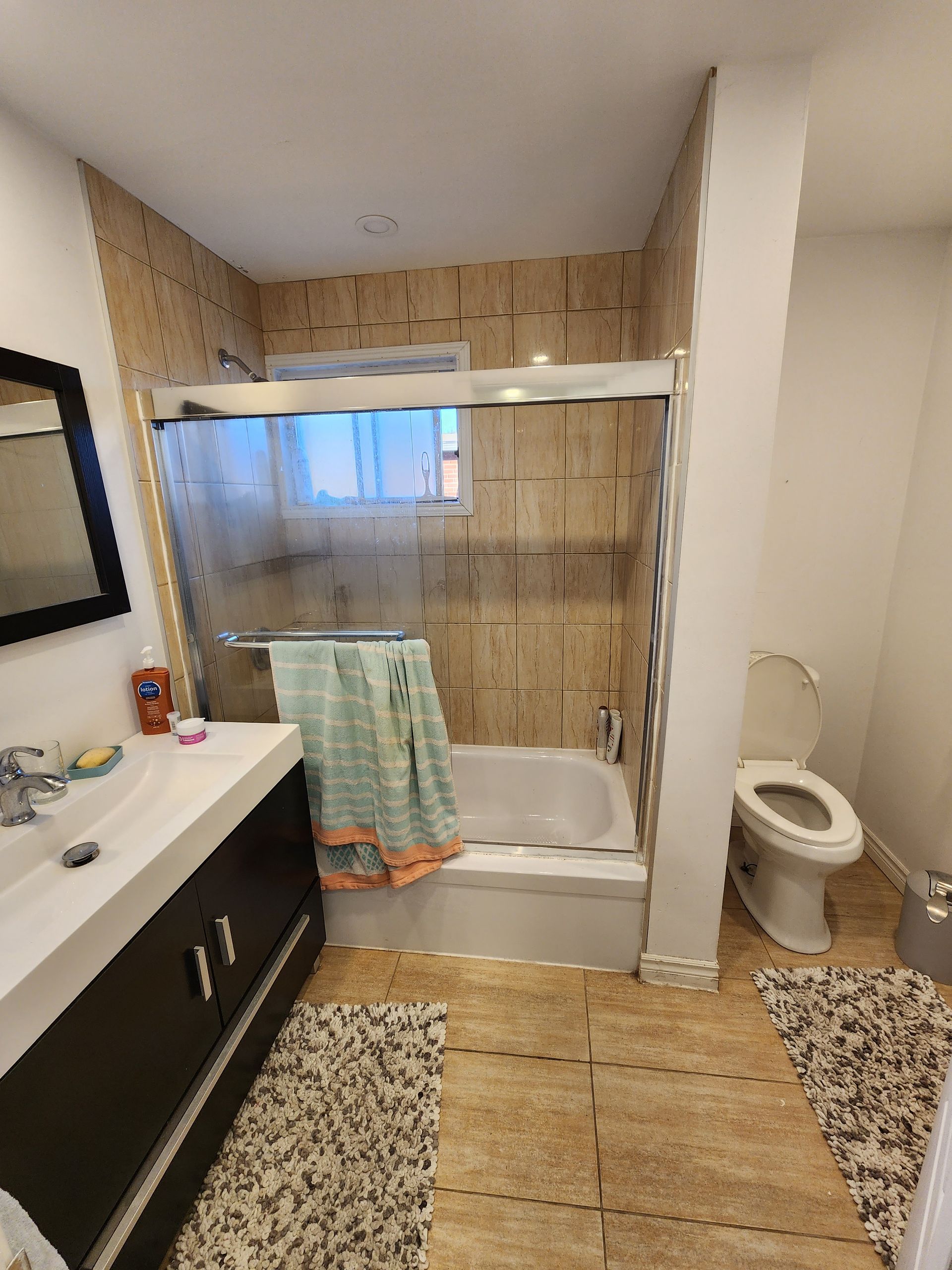 A bathroom with a tub , toilet , sink and mirror.