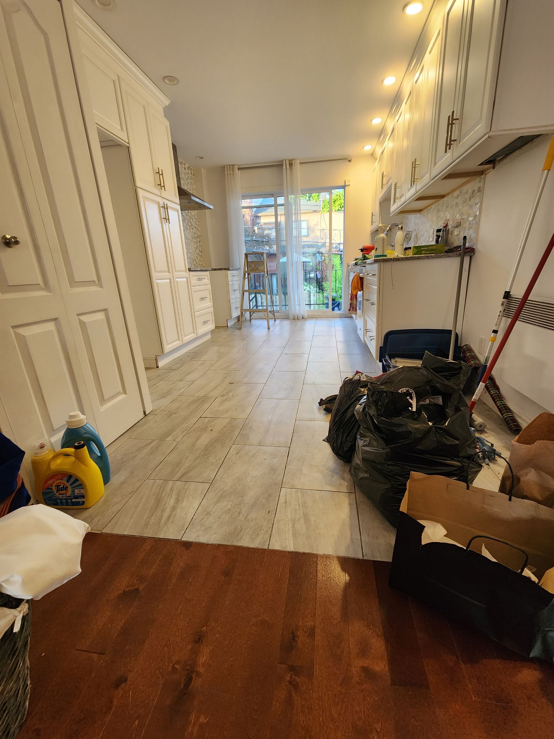 A kitchen with hardwood floors and white cabinets is being remodeled.