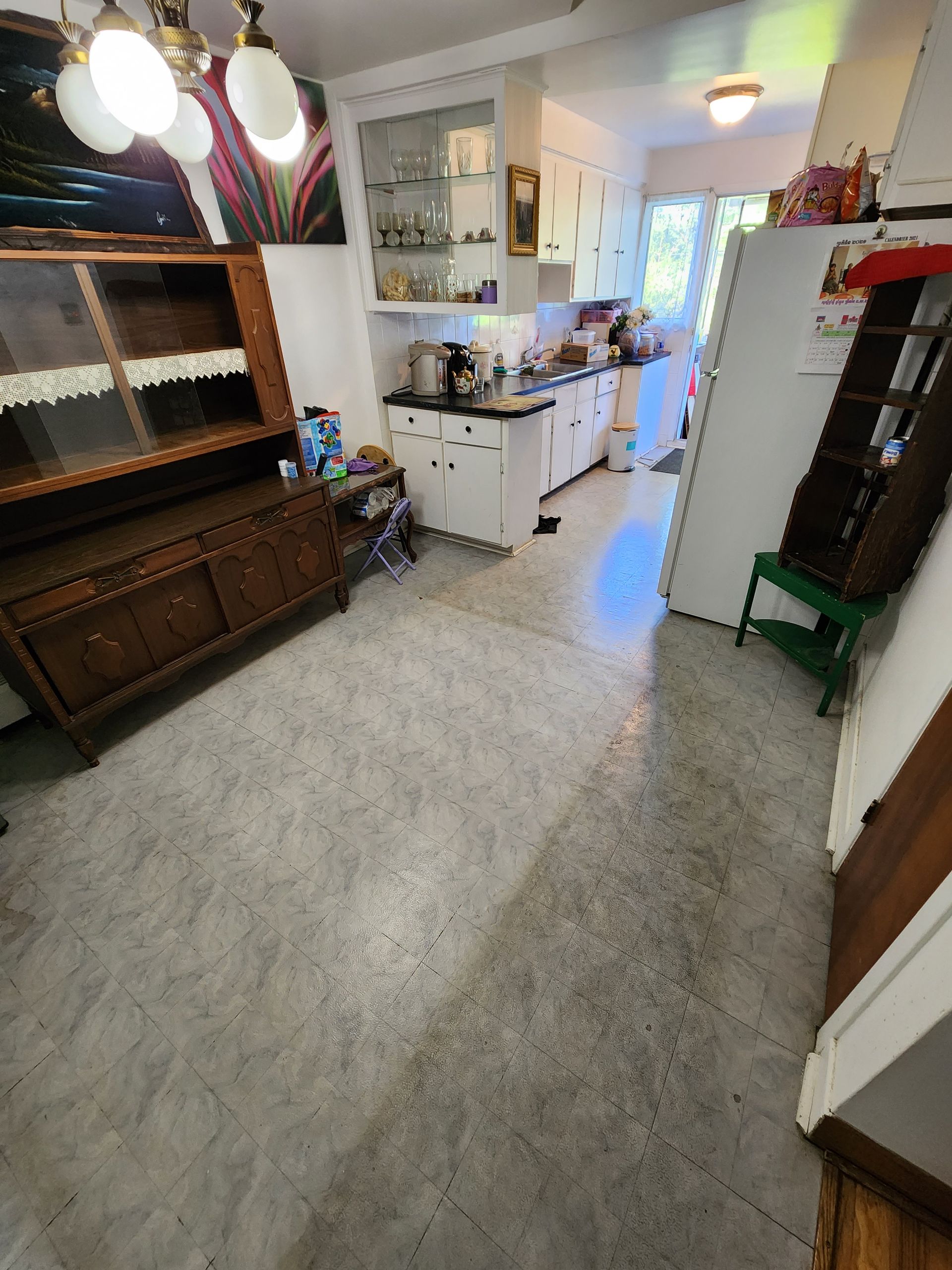 A kitchen with white cabinets , a refrigerator , a stove and a hutch.