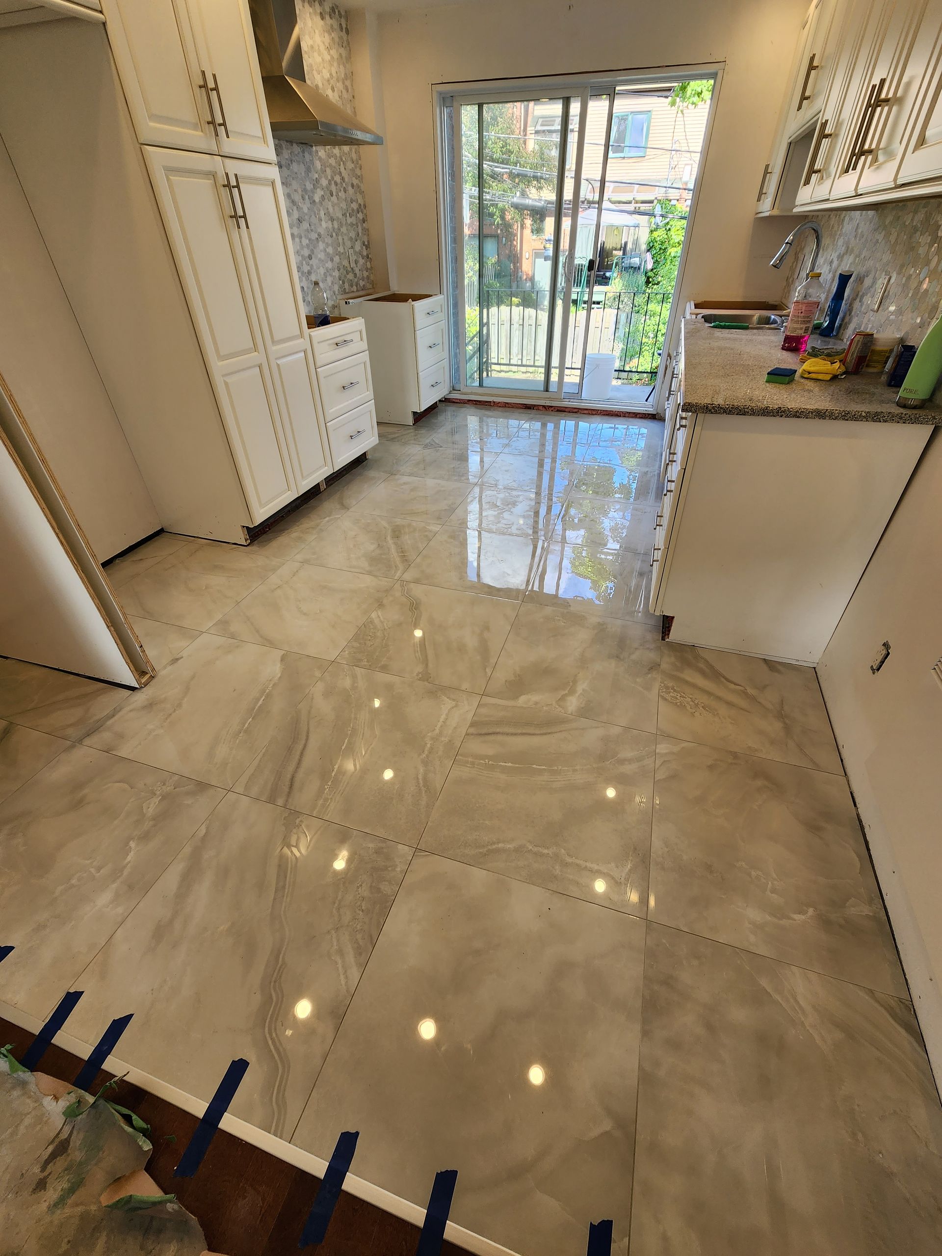 A kitchen with a marble floor and sliding glass doors.