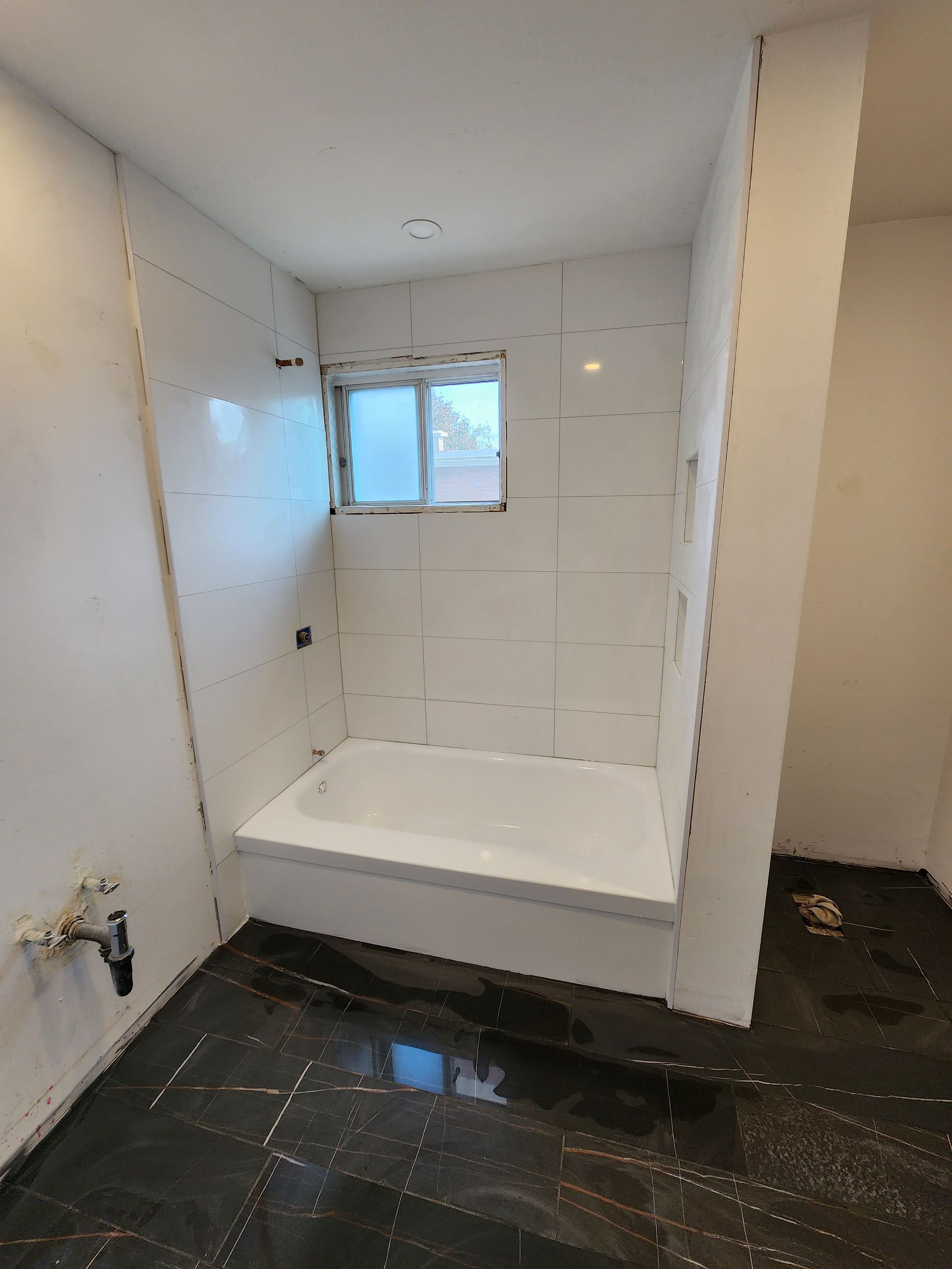 A bathroom with a bathtub and a window.