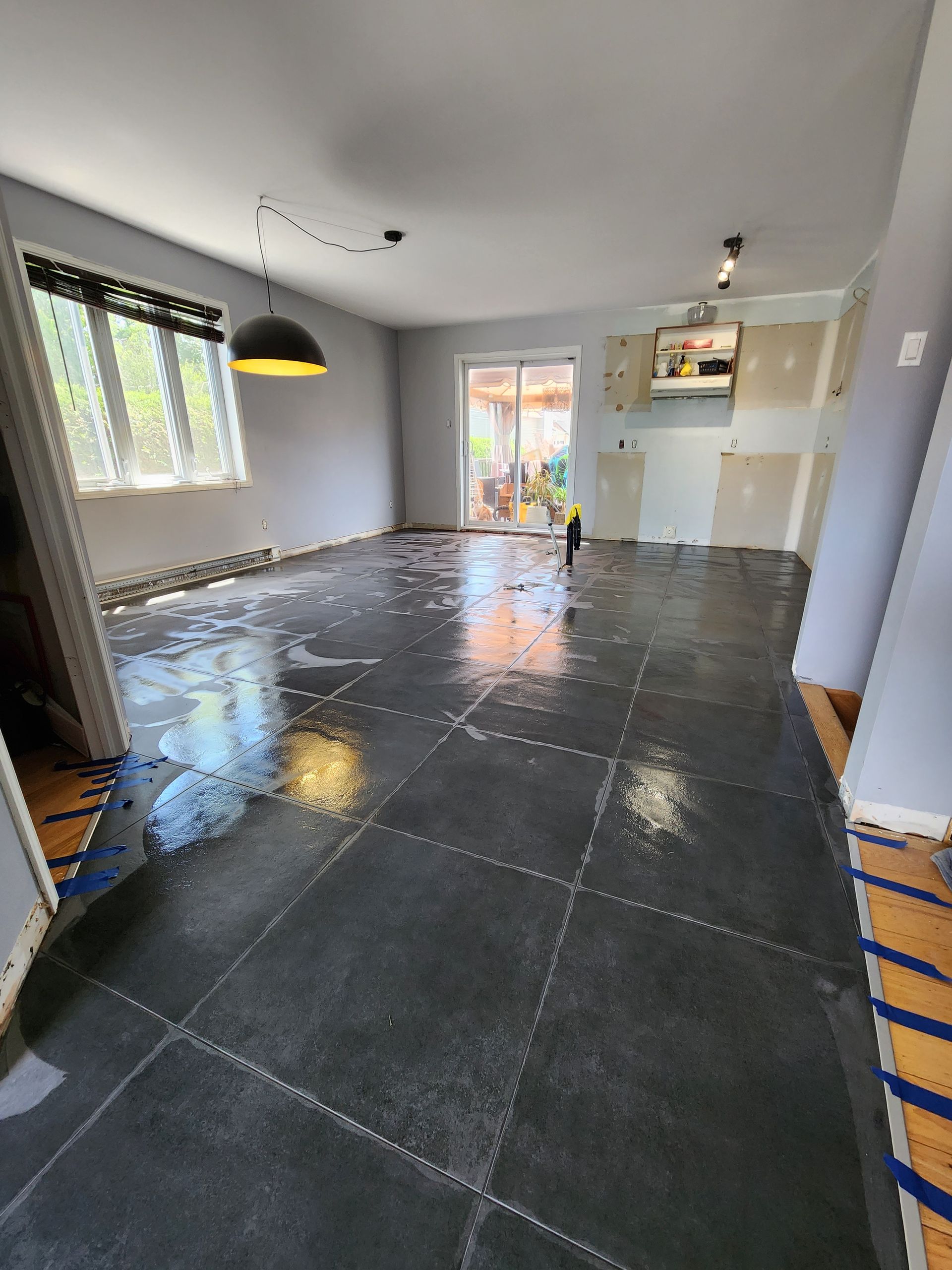 A living room with a black tile floor and a sliding glass door.