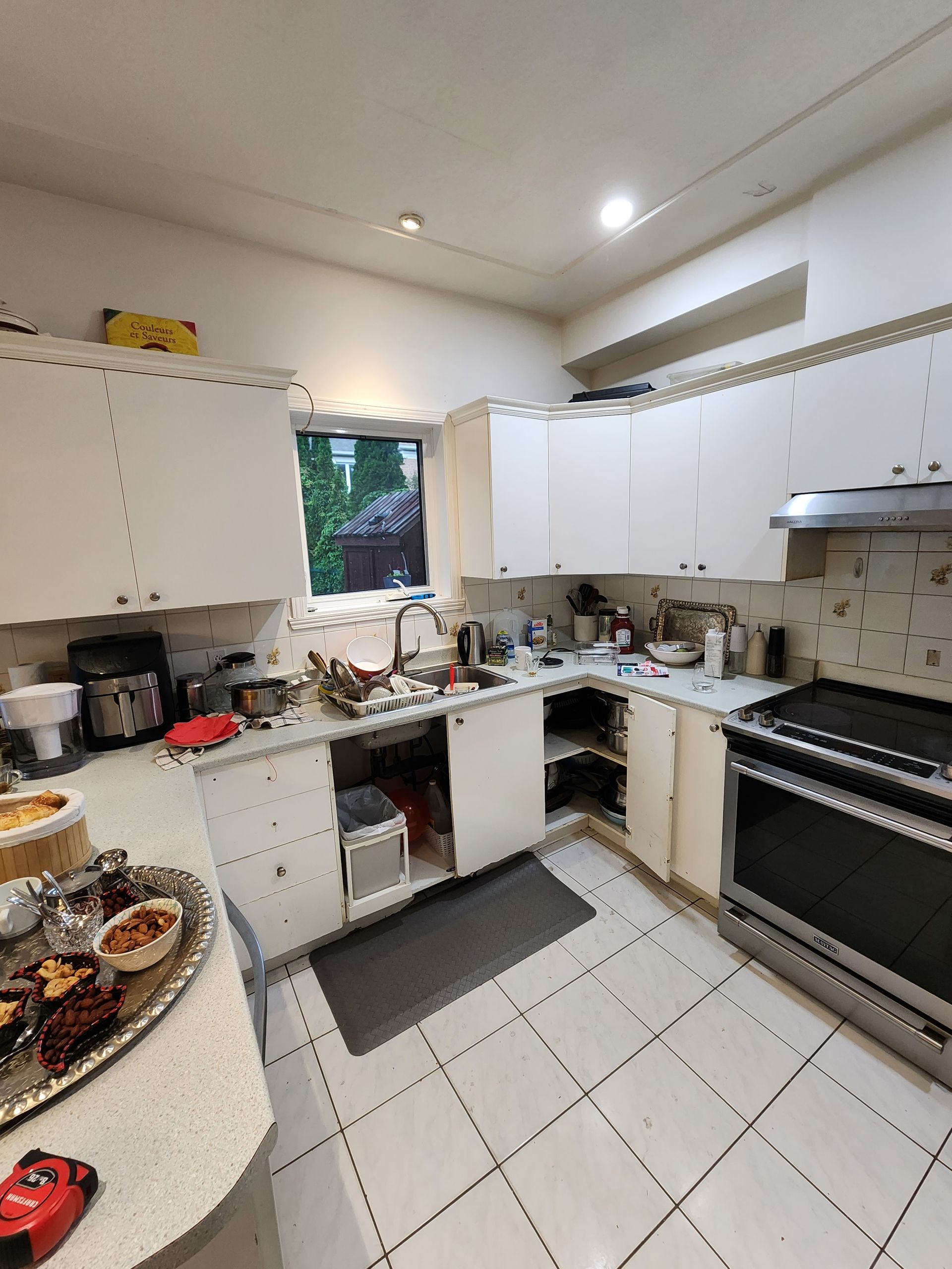 A kitchen with white cabinets , a stove , and a window.