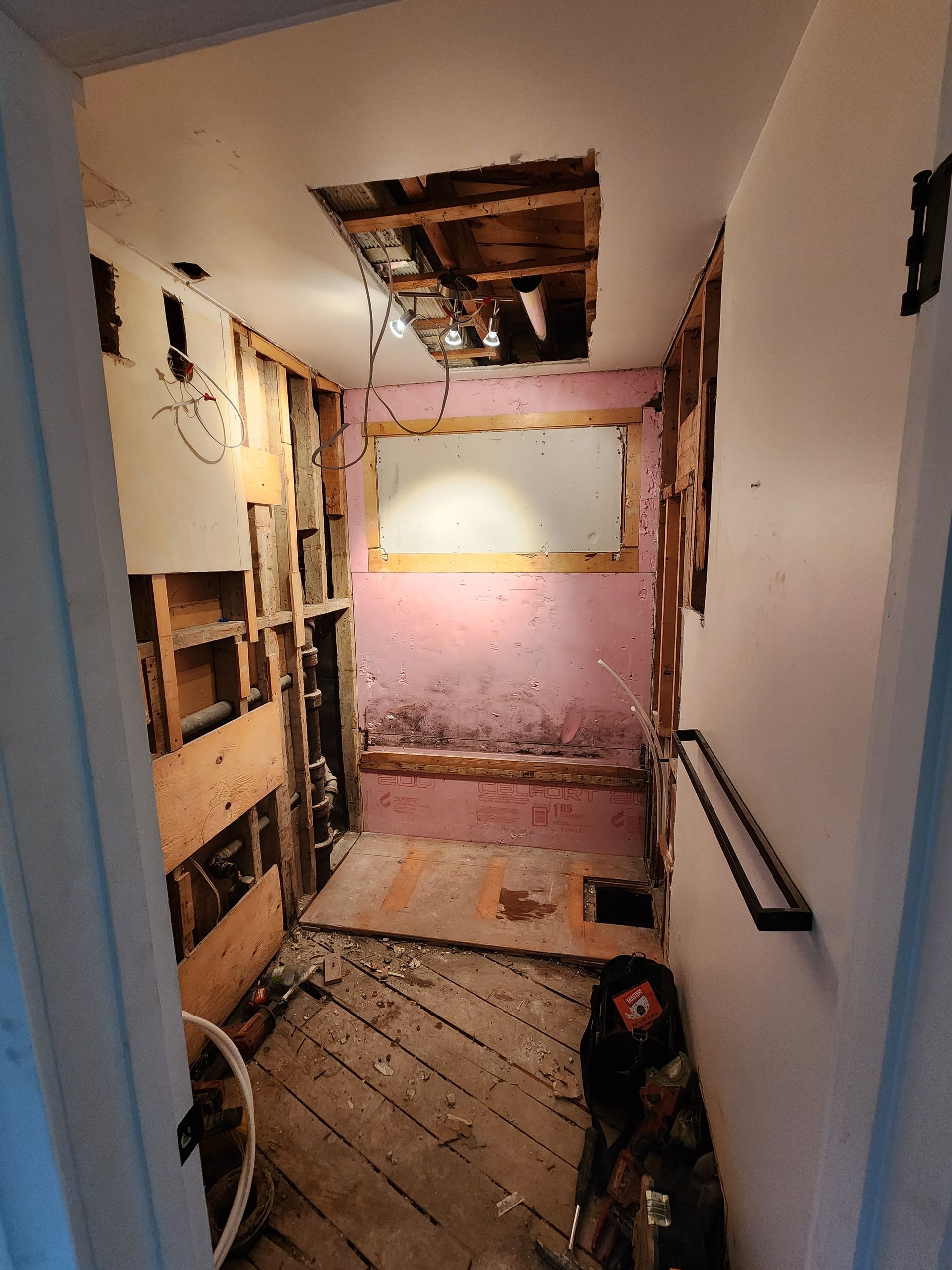 A bathroom under construction with a hole in the ceiling.