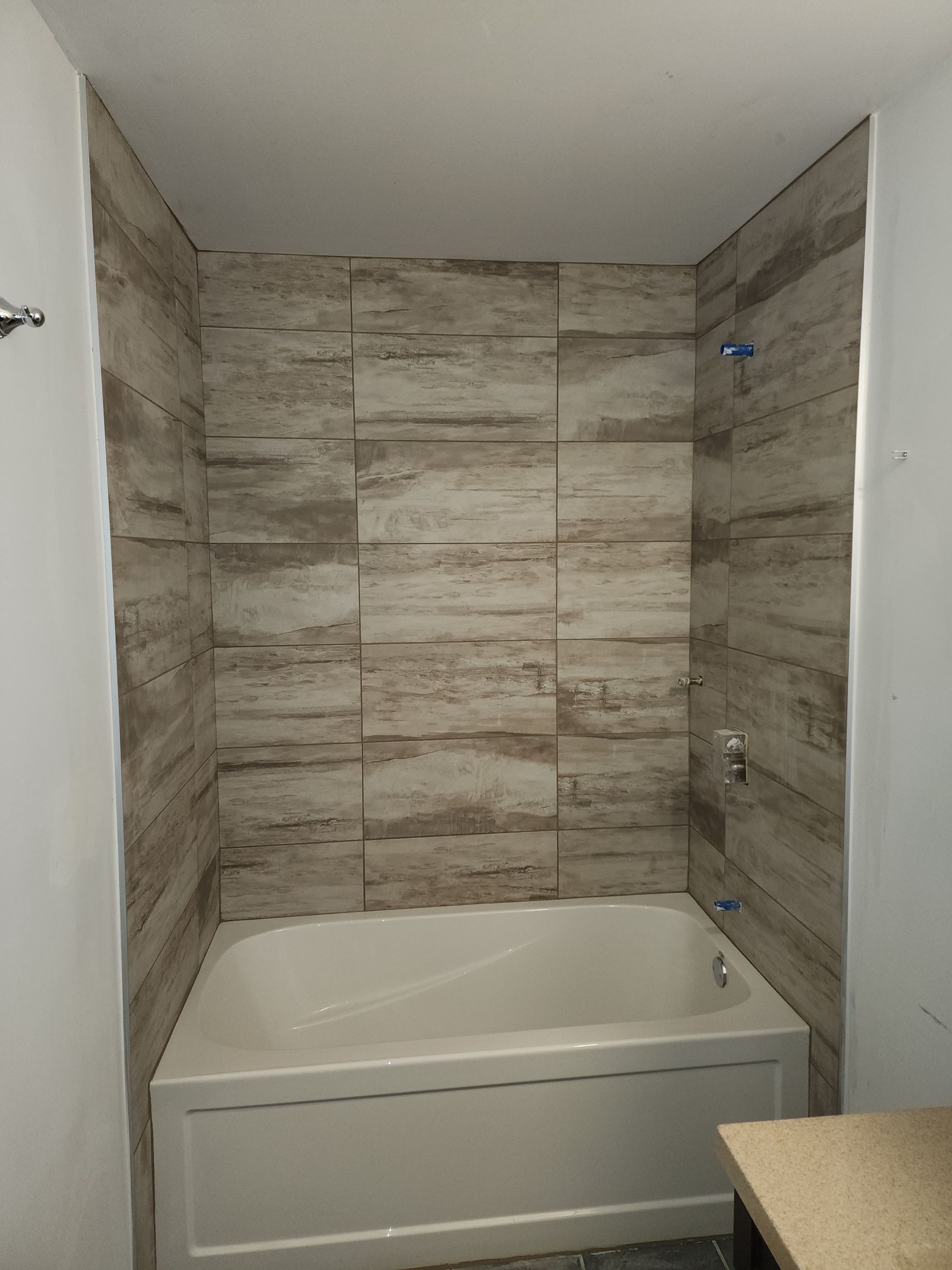 A bathroom with a bathtub and tiled walls.