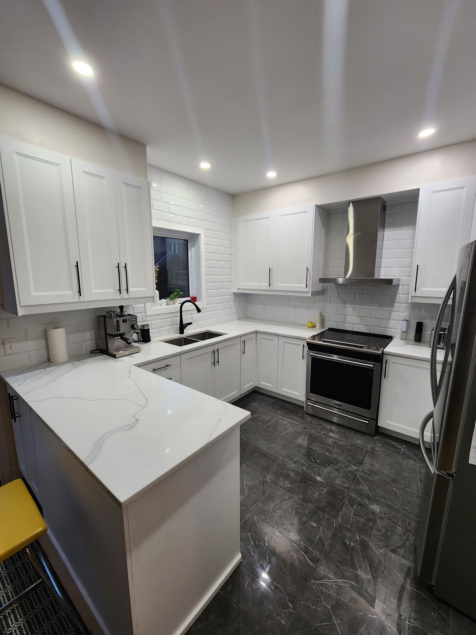 A kitchen with white cabinets , a stove , a refrigerator , and a sink.