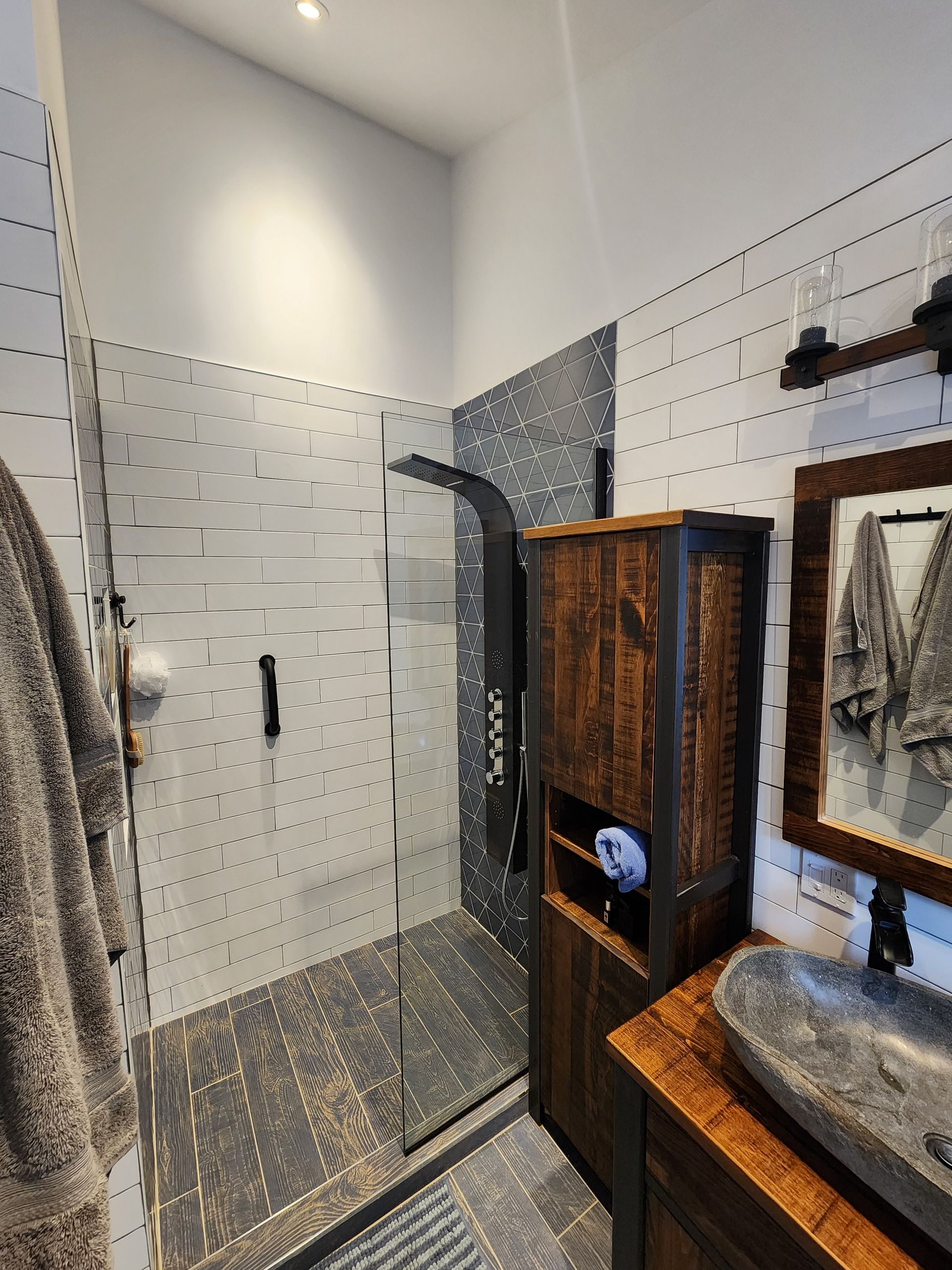 A bathroom with a walk in shower , sink and mirror.