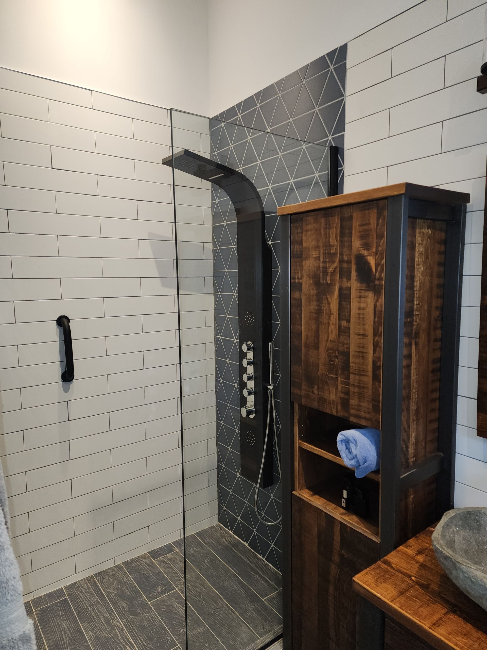 A bathroom with a walk in shower and a wooden cabinet.