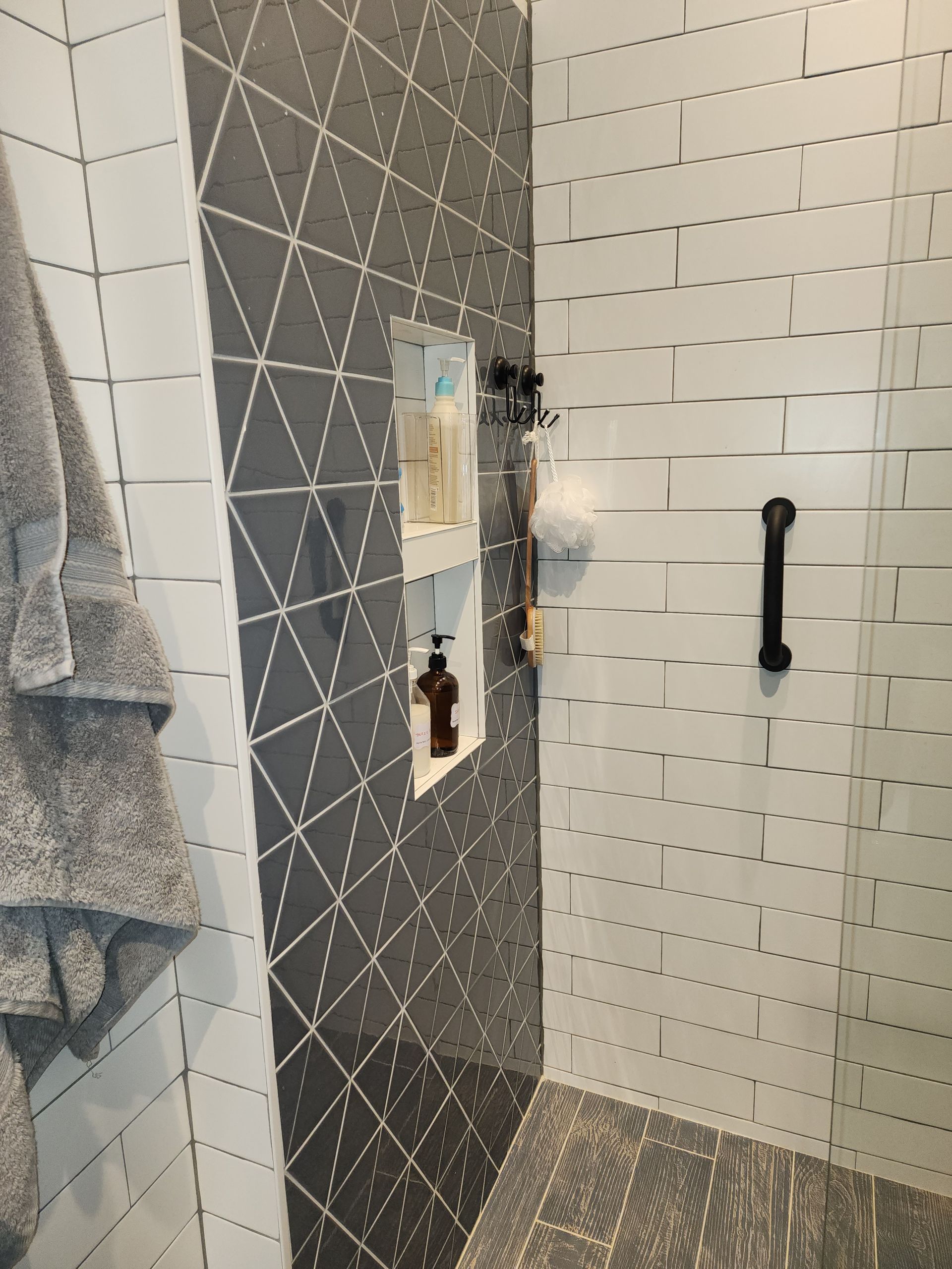 A bathroom with black and white tiles and a walk in shower
