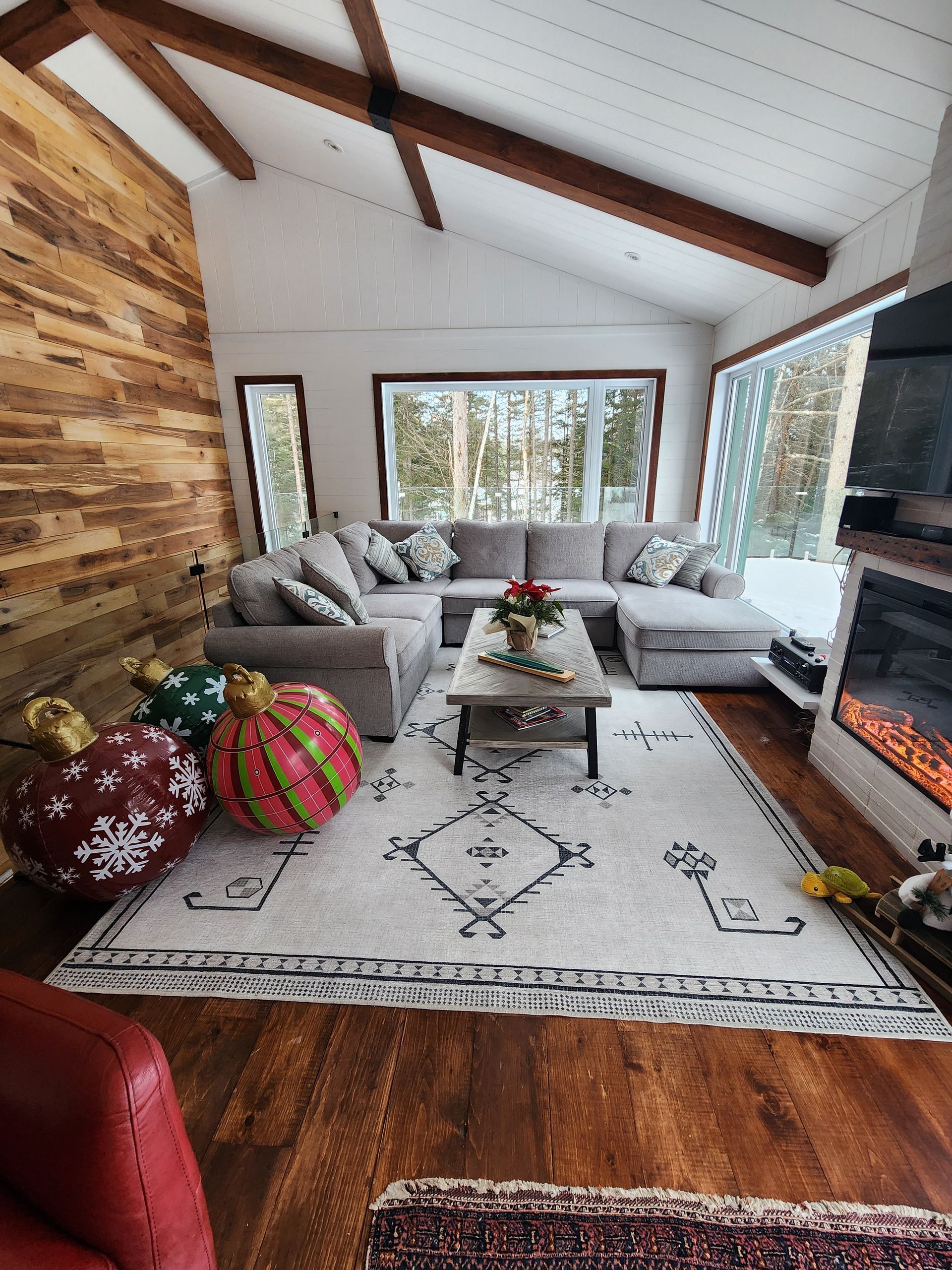 A living room with a sectional couch , coffee table , fireplace and christmas decorations.