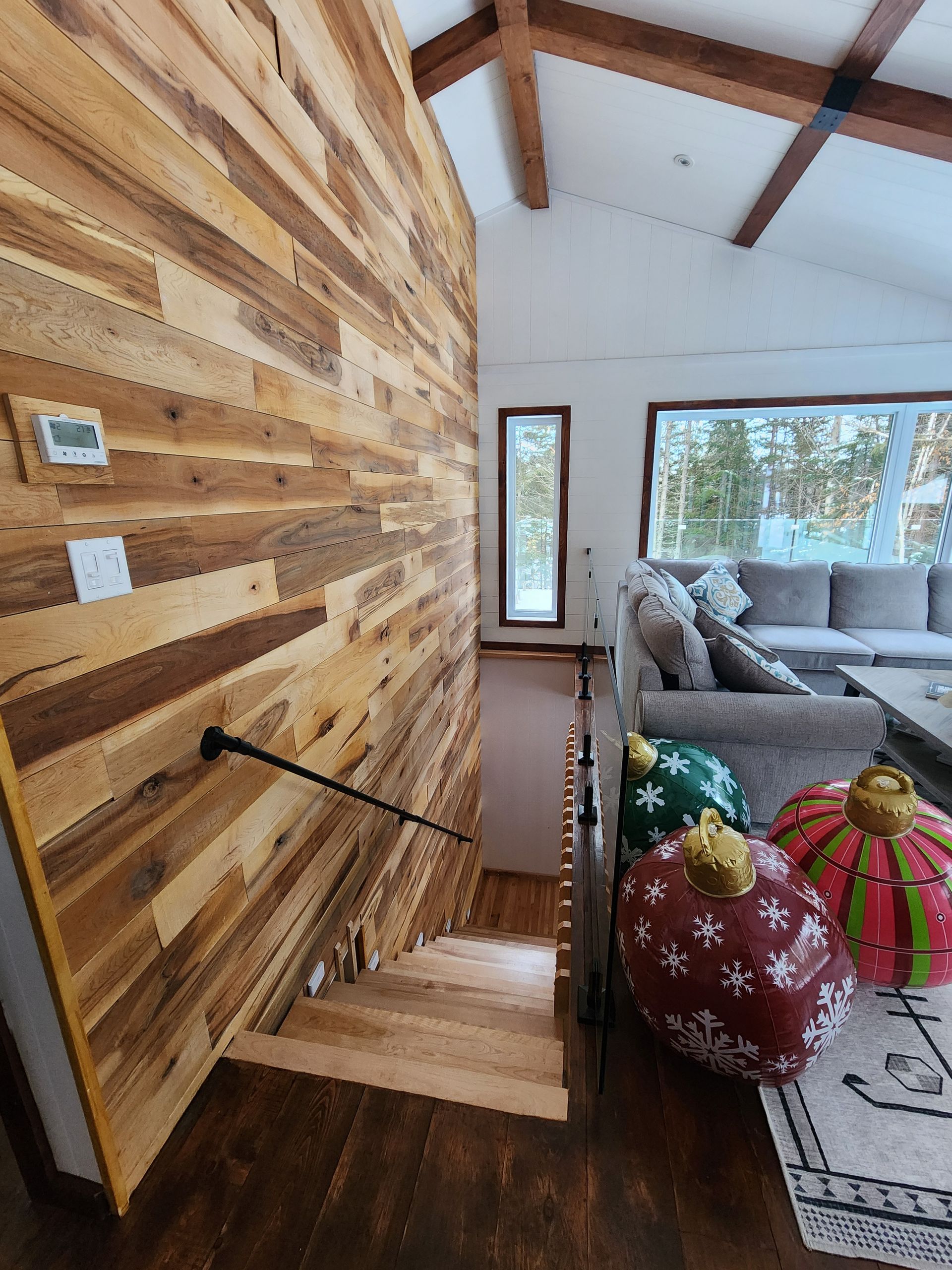 A living room with a wooden wall and stairs leading up to the second floor.