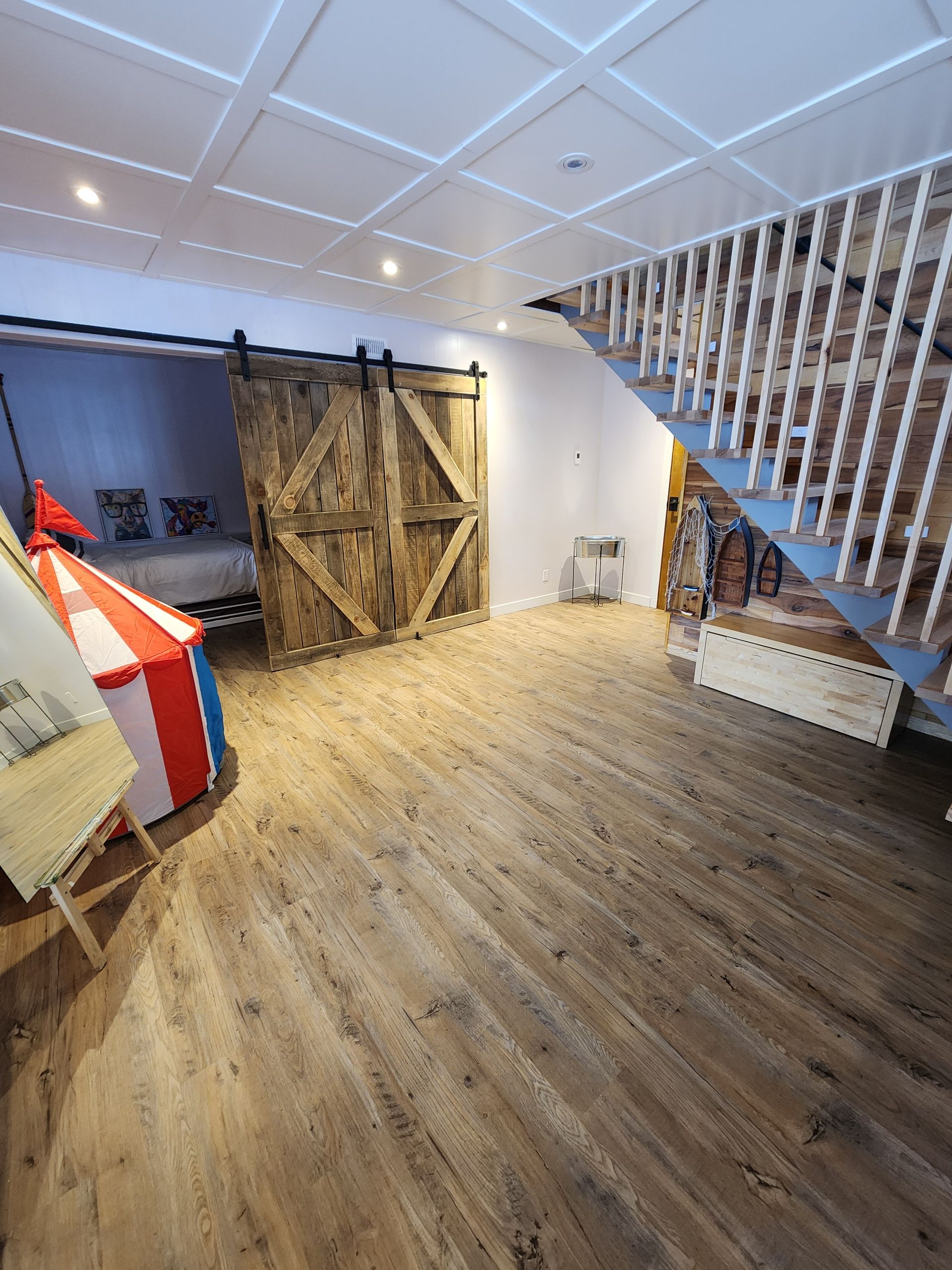 A room with a staircase and a sliding barn door.