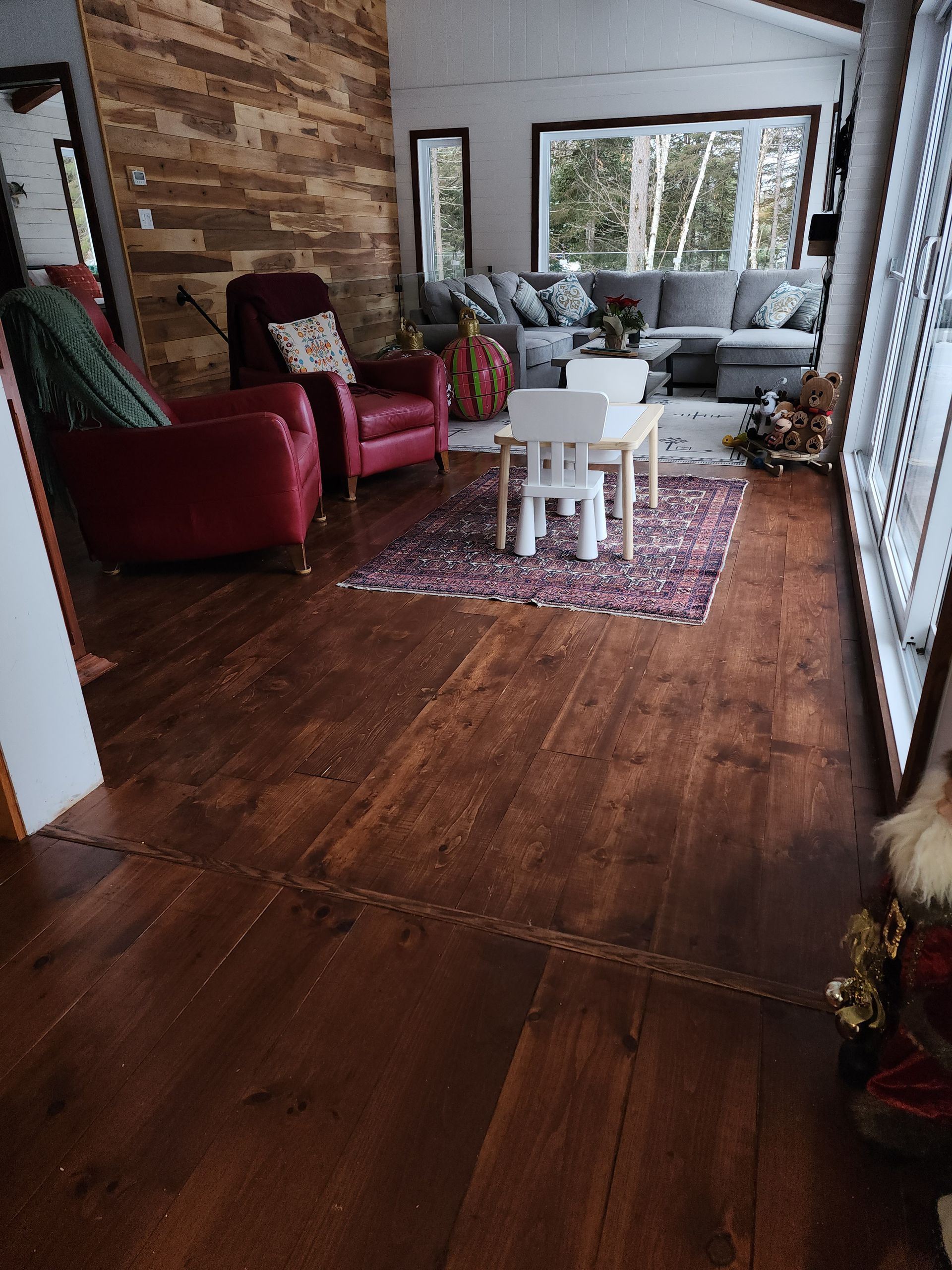 A living room with hardwood floors , a couch , chairs , and a table.