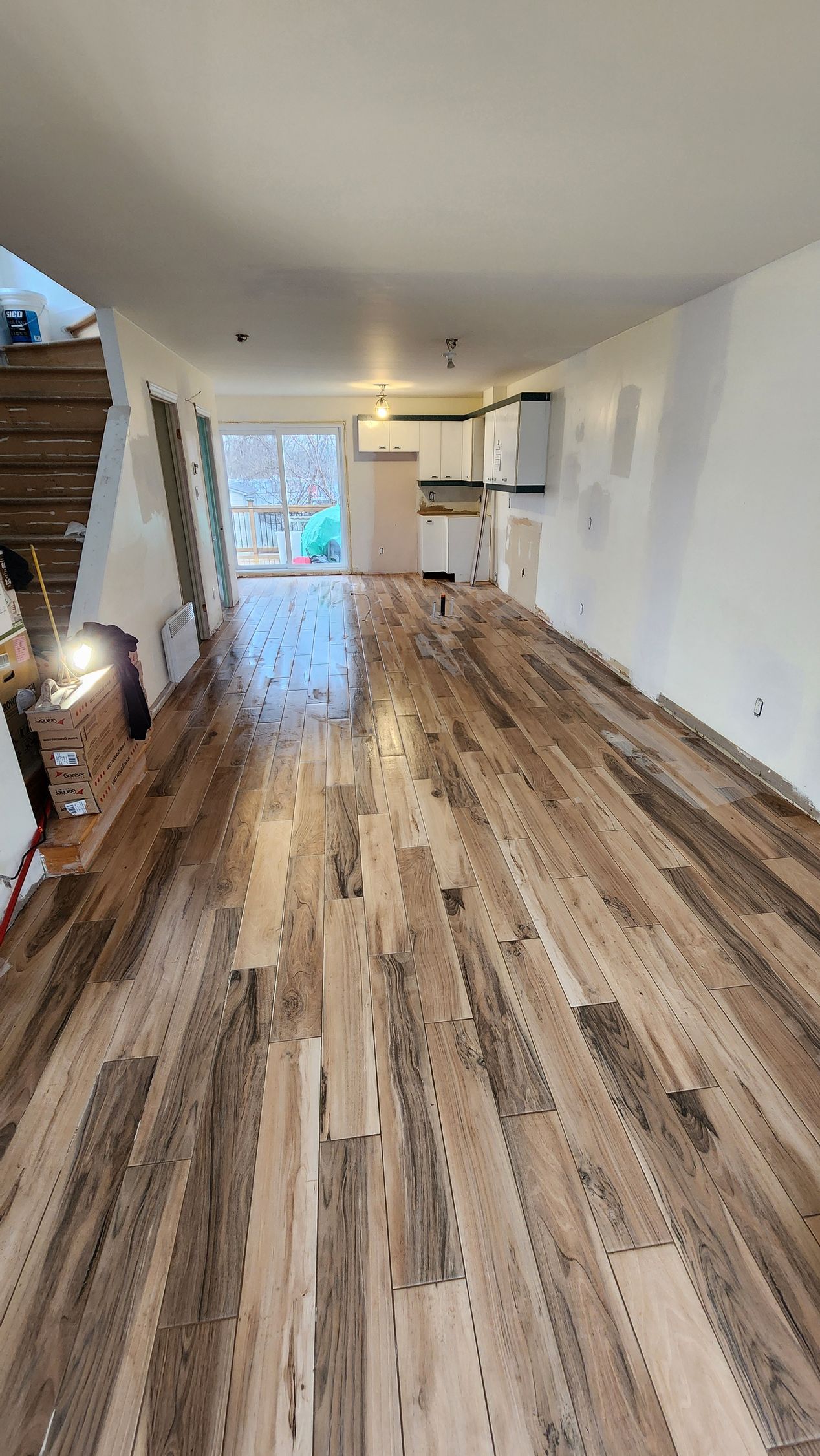 A large empty room with a wooden floor and stairs.