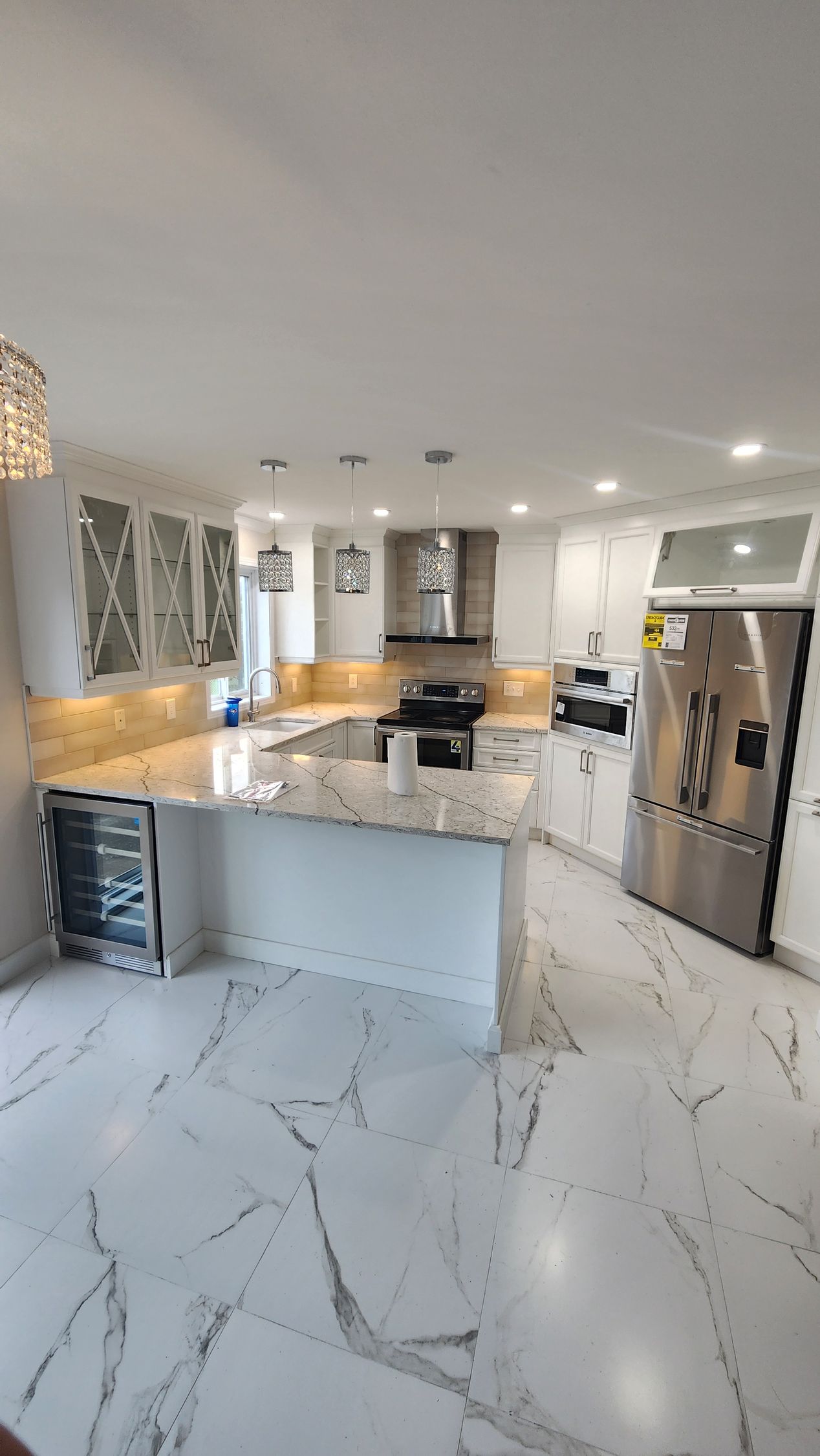 A kitchen with white cabinets , granite counter tops , stainless steel appliances and marble floors.