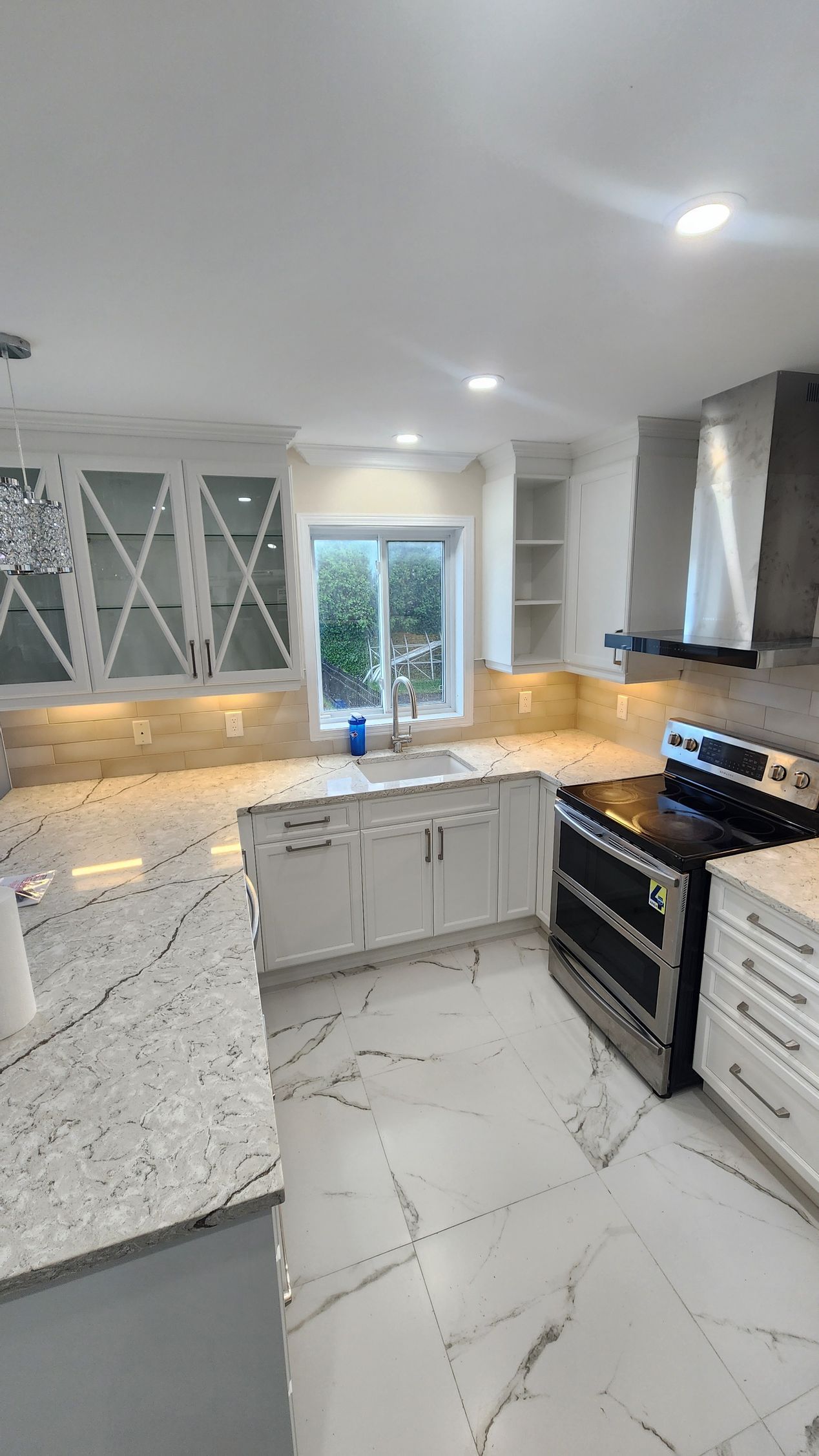 A kitchen with white cabinets , granite counter tops , a stove and a sink.