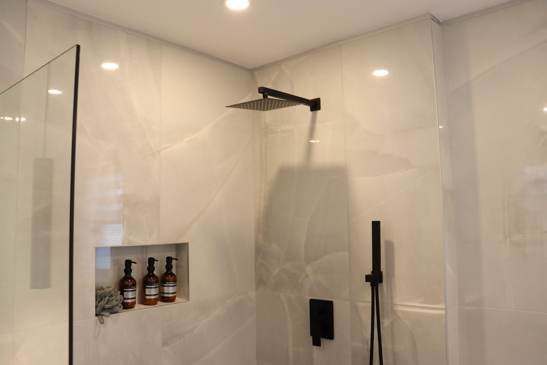 A bathroom with a walk in shower and a shower head.