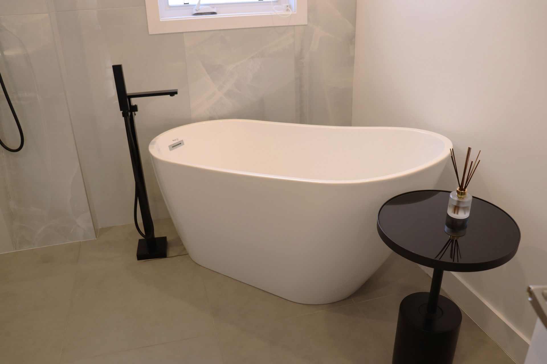 A white bathtub is sitting next to a black table in a bathroom.