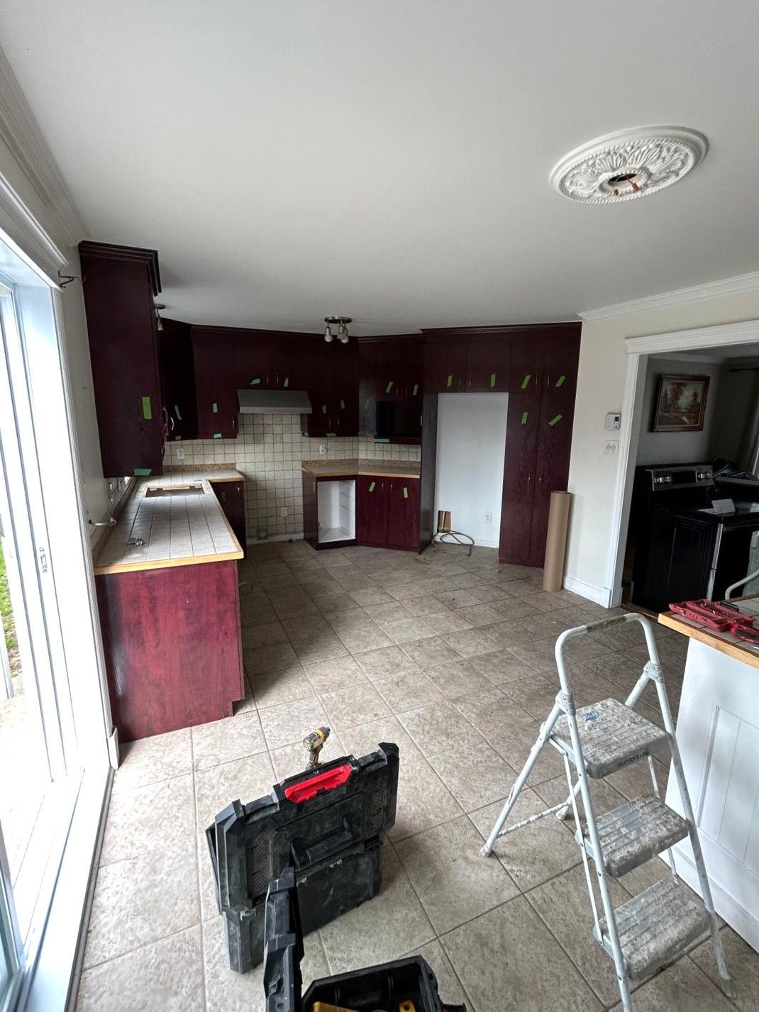 A kitchen with a ladder and a toolbox on the floor.
