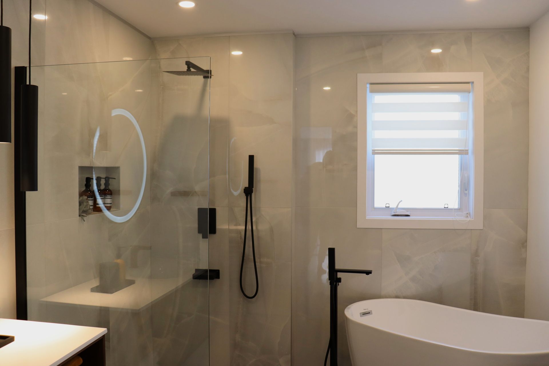 A bathroom with a tub , shower , mirror and window.