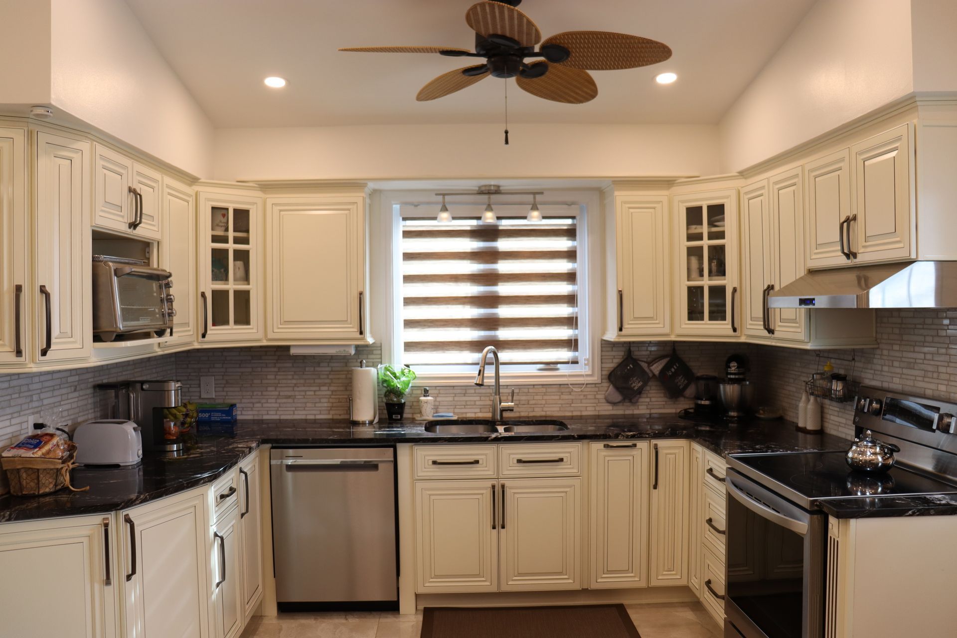 A kitchen with white cabinets and a ceiling fan